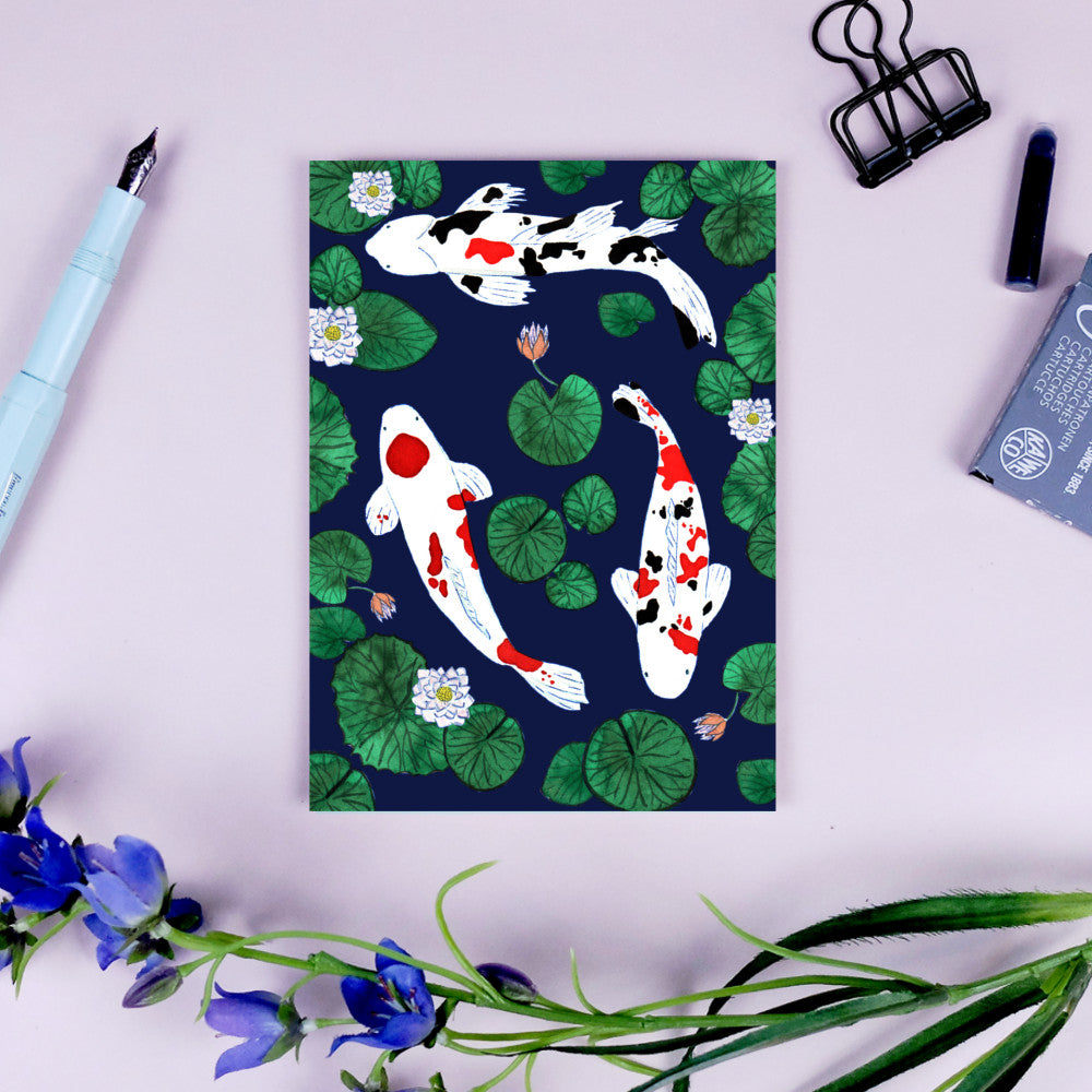 Illustration von Koi-Fischen und Seerosenblättern auf blauem Hintergrund, umgeben von Schreibutensilien.