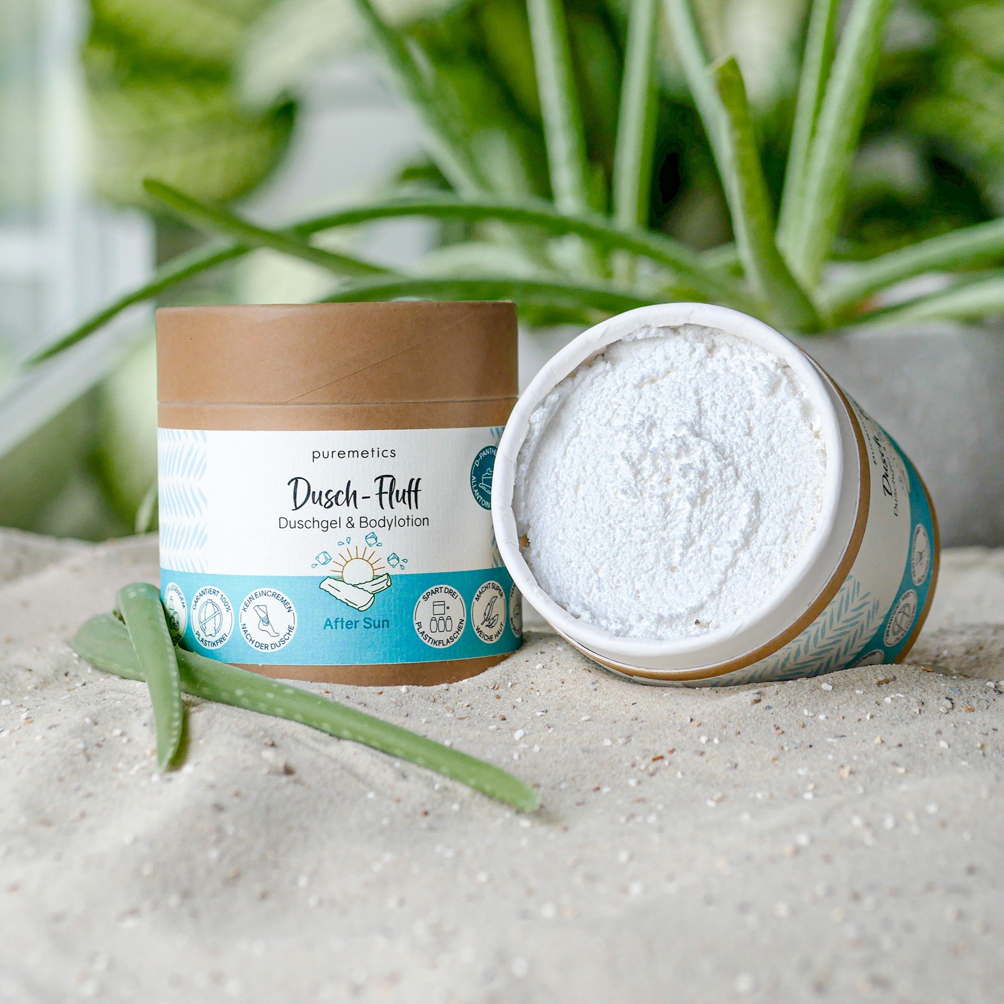Verpackung von Puremetics Duschgel und Bodylotion mit Sand und Aloe Vera im Hintergrund.
