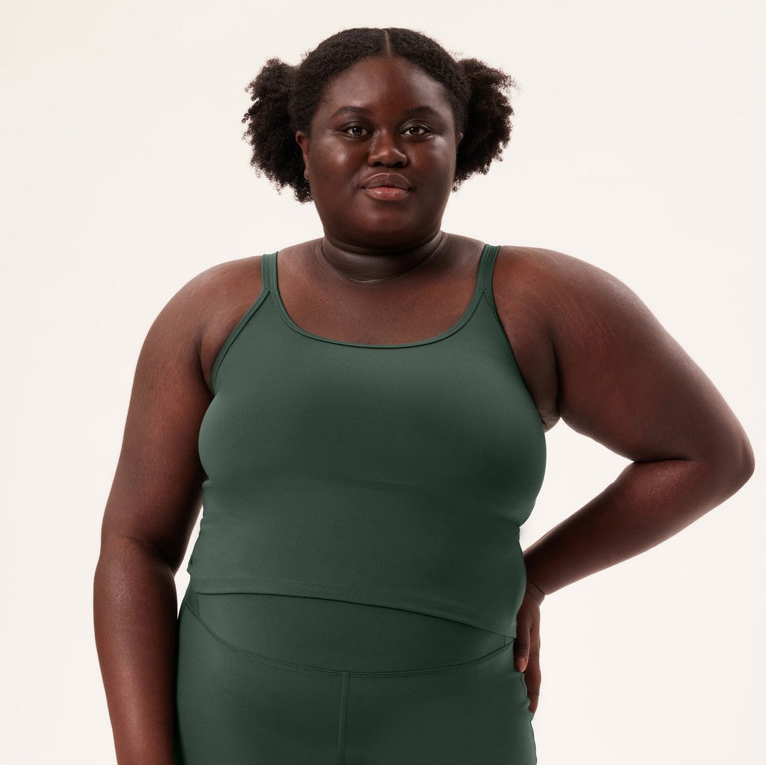 Eine Person in grüner Sportbekleidung steht vor einem neutralen Hintergrund.