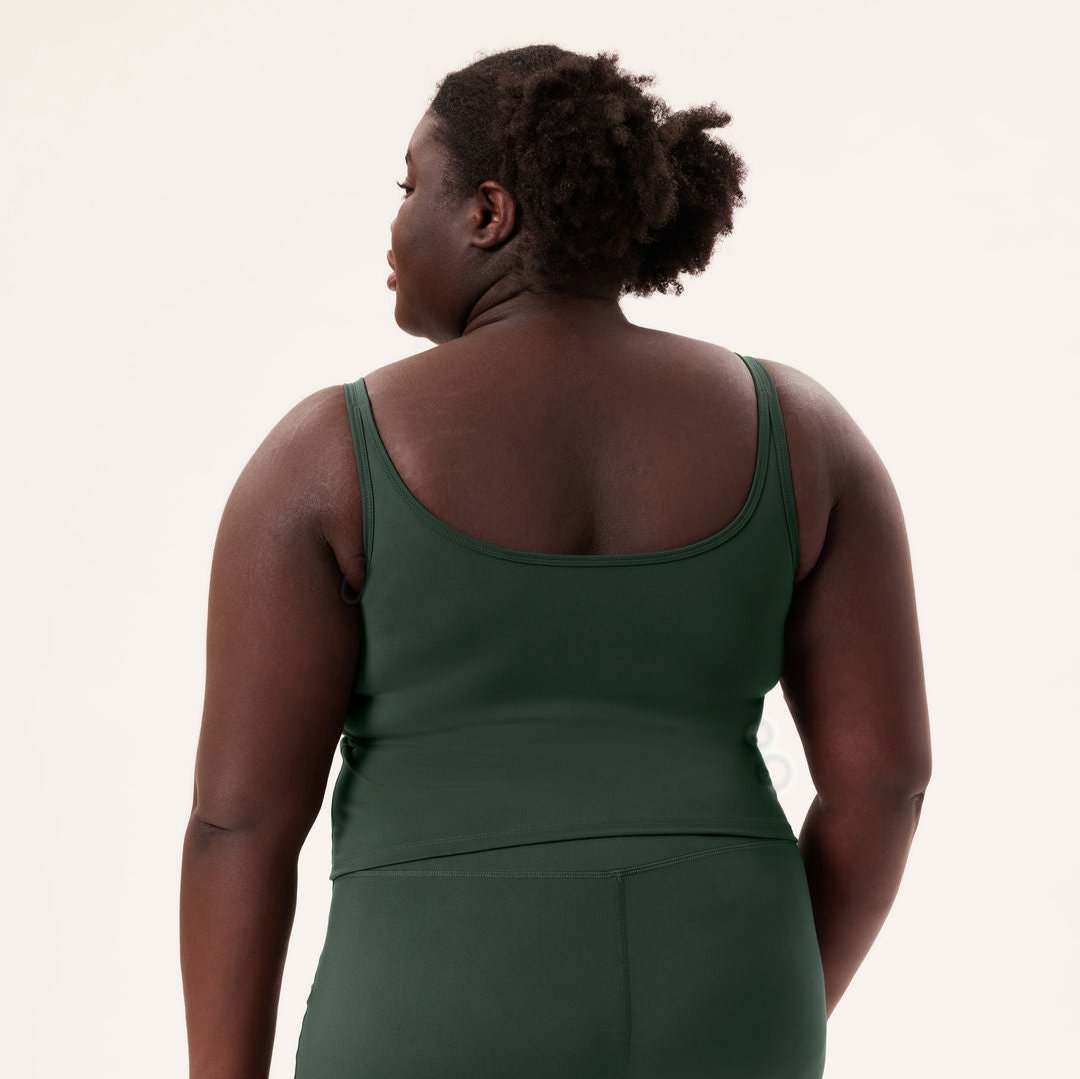 Person von hinten in grüner Sportbekleidung vor hellem Hintergrund.