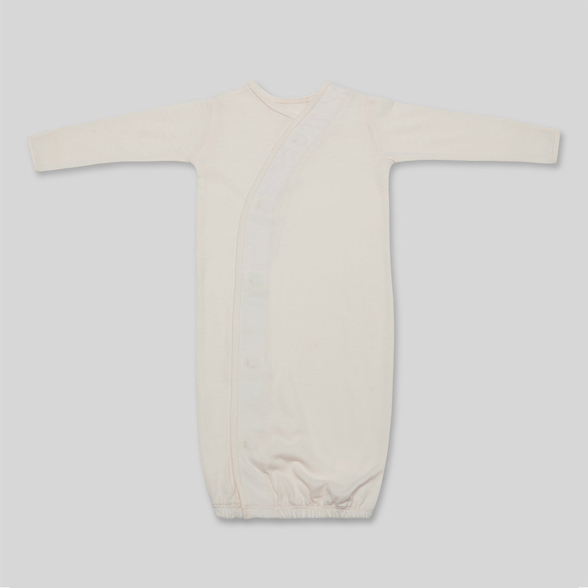 Beigefarbenes, langärmliges Baby-Schlafkleid mit seitlichen Knöpfen vor neutralem Hintergrund.