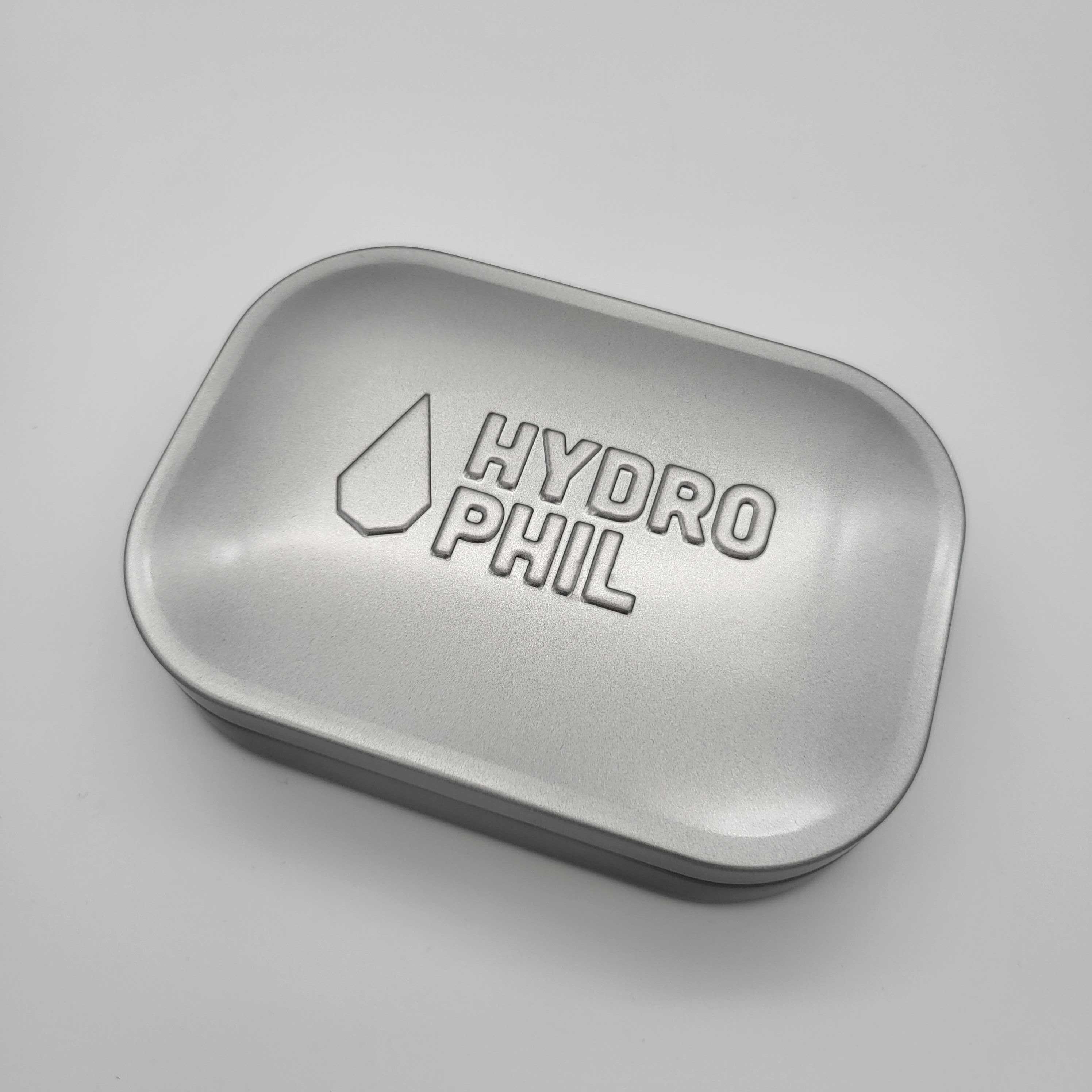 Silberne rechteckige Metallbox mit abgerundeten Ecken und dem geprägten Schriftzug "HYDROPHIL" auf dem Deckel.
