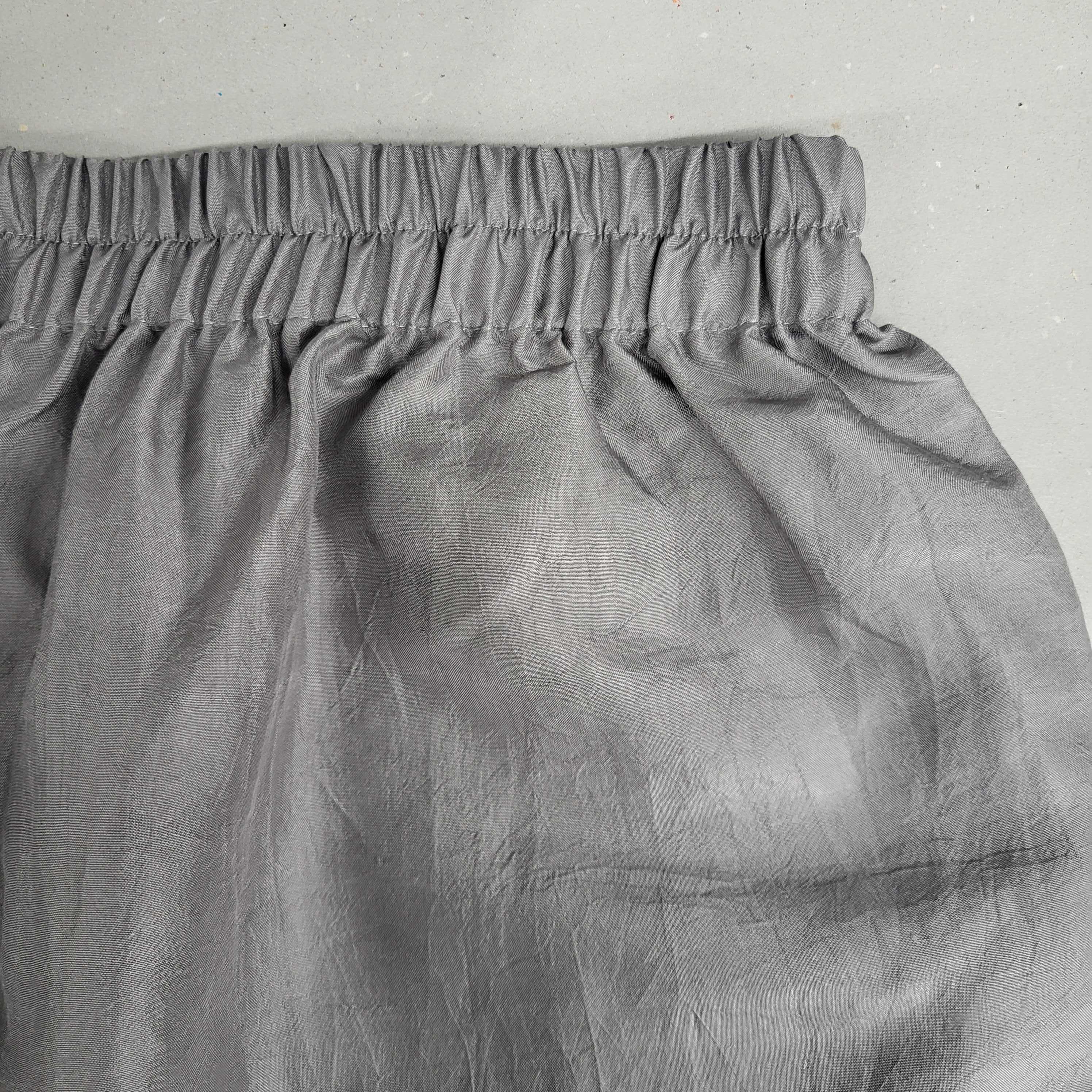 Grauer Stoff mit elastischem Bund und Falten auf einer glatten, grauen Oberfläche.