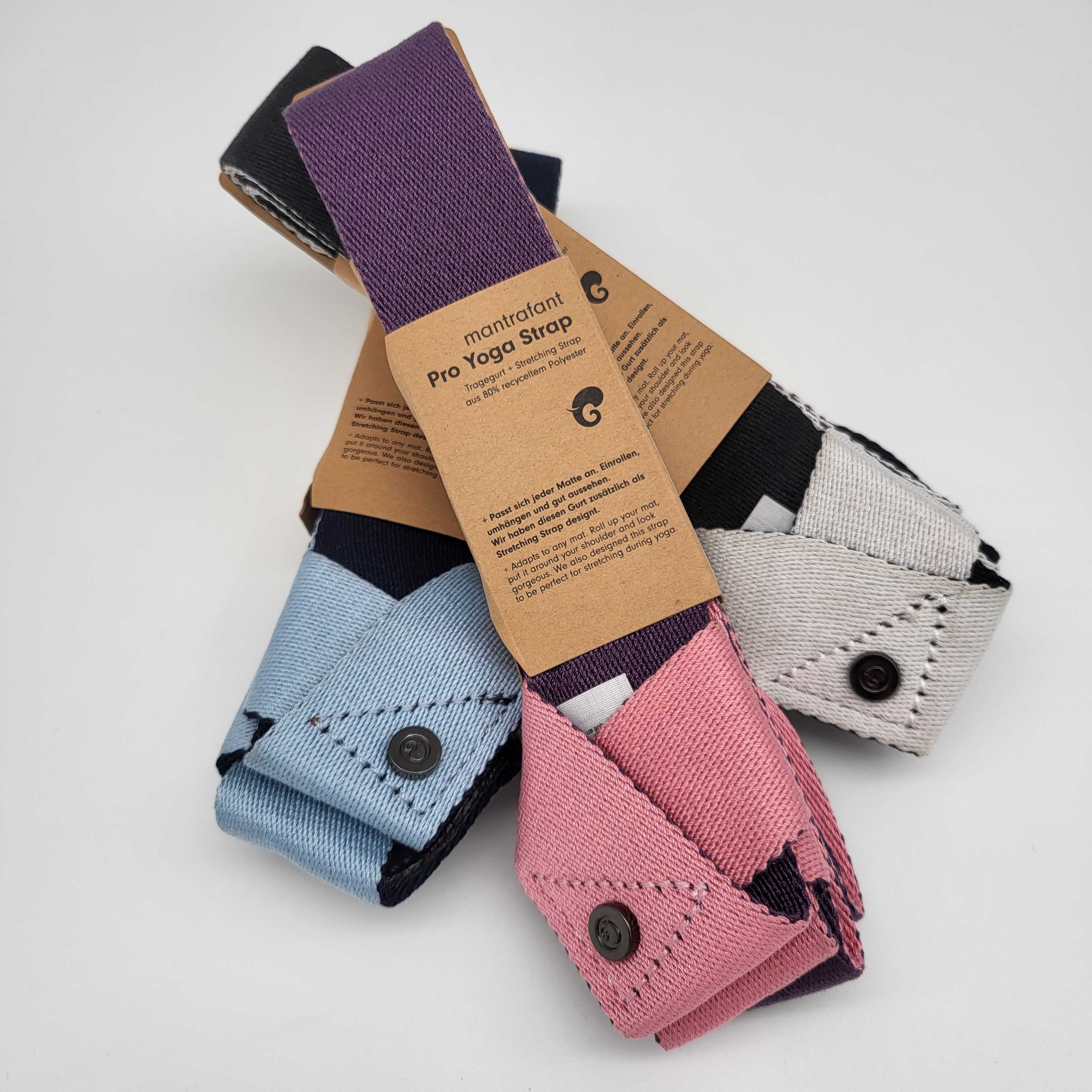 Bunte Yoga-Gurte mit Verpackungsetiketten, in Rosa, Blau und Naturtönen auf weißem Hintergrund.