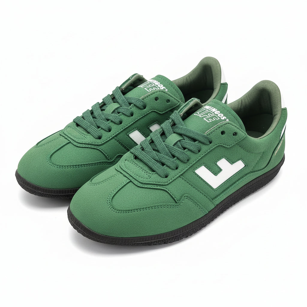 Ein Paar grüne Turnschuhe mit weißem Seitenlogo, schwarzer Sohle und weißer Papierfüllung auf einer grauen Fläche.