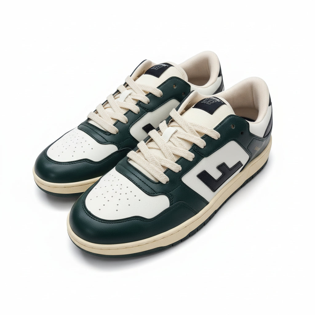 Ein Paar grüne, weiße und schwarze Turnschuhe mit cremefarbenen Schnürsenkeln und Sohlen stehen auf einem grauen Betonboden. Die Schuhe sind mit einem großen L-Logo an der Seite versehen.