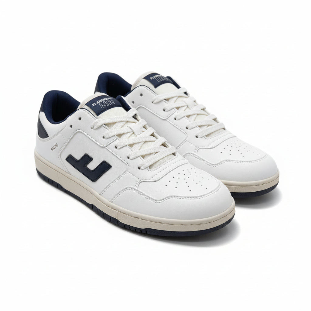 Ein Paar weiße Turnschuhe mit dunkelblauen Details, darunter ein großes E-Logo an der Seite, marineblaues Futter und beigefarbene Sohlen, die auf einer grauen, strukturierten Oberfläche angebracht sind.