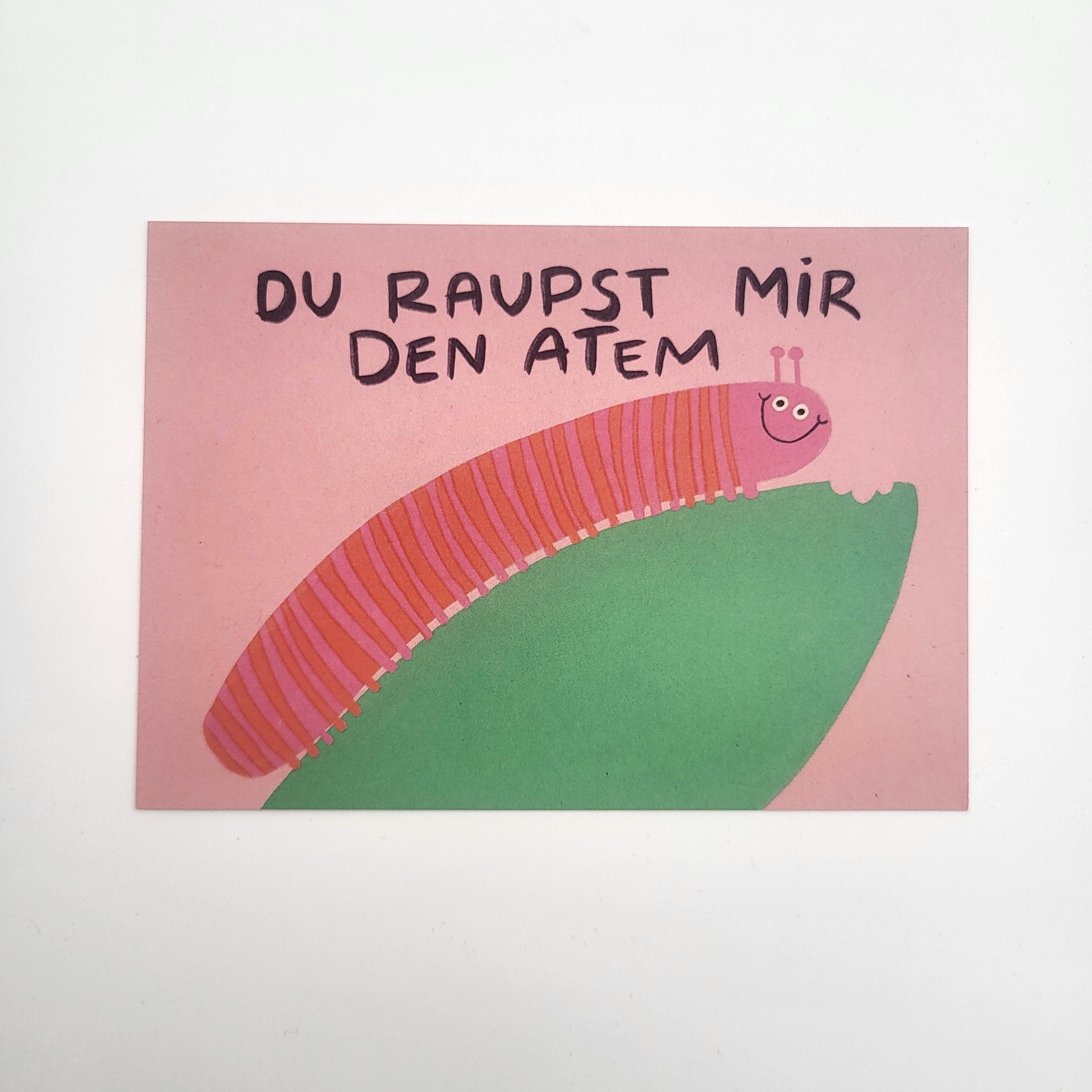 Eine rosa Karte mit einer Cartoon-Raupe auf einem grünen Blatt. Über der Raupe steht ein handgeschriebener Text in Deutsch: DU RAUPST MIR DEN ATEM.