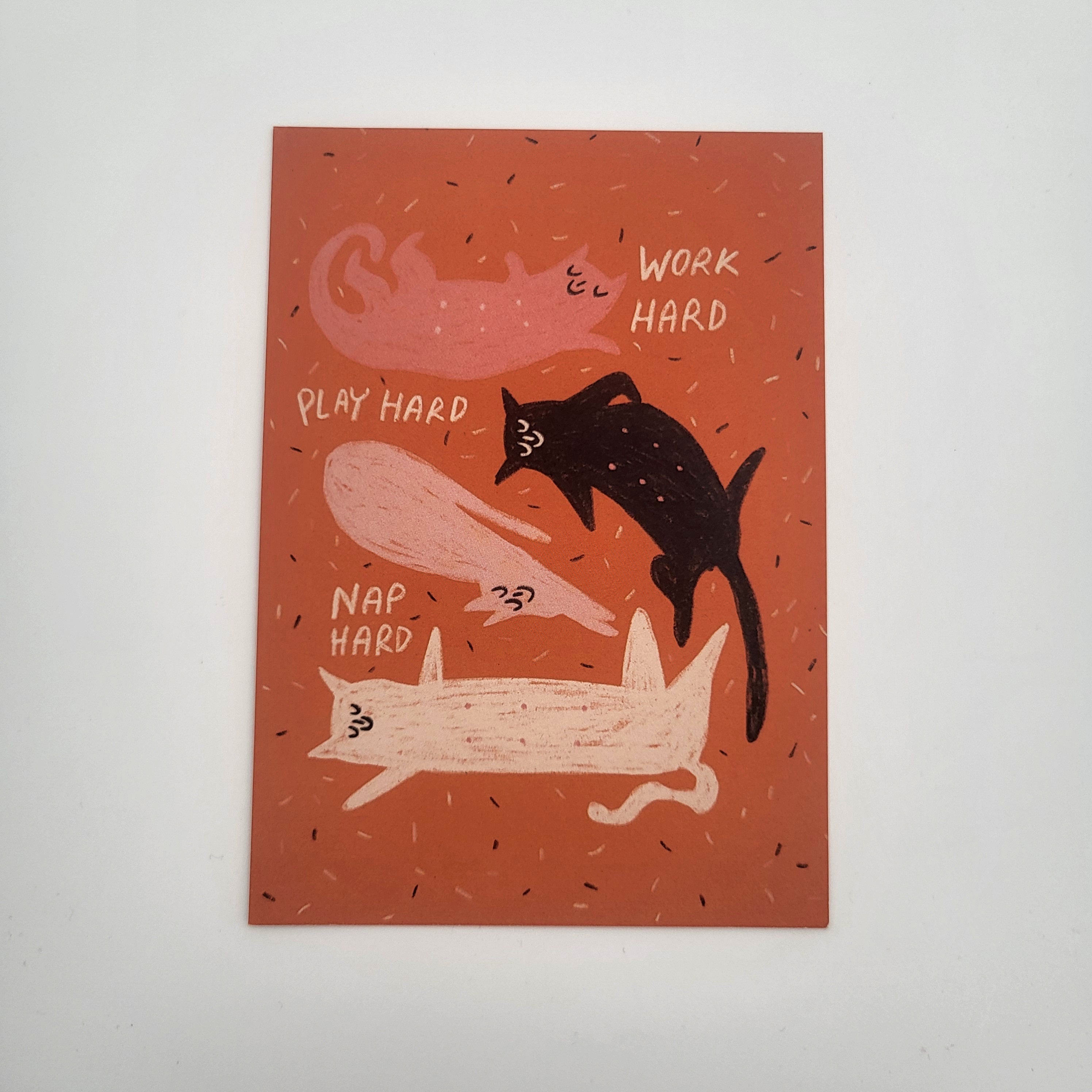 Eine Illustration von drei Katzen auf einem orangefarbenen Hintergrund mit den Sätzen WORK HARD, PLAY HARD, und NAP HARD neben jeder Katze. Die Katzen sind passend zum Text posiert: Arbeiten, Spielen und Schlafen.