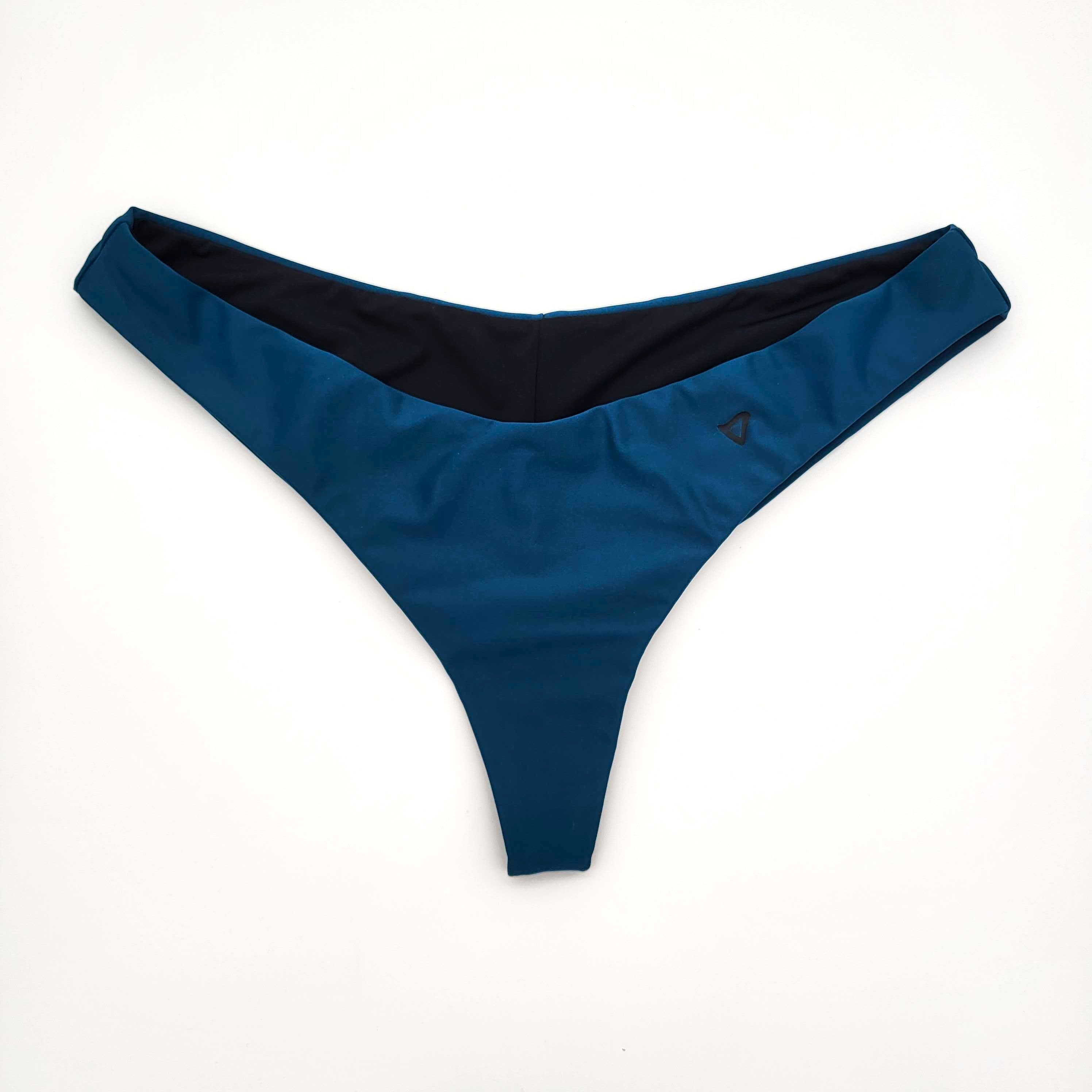 Ein Paar blaue Bikinihosen mit schwarzem Innenfutter, flach auf weißem Hintergrund gelegt.