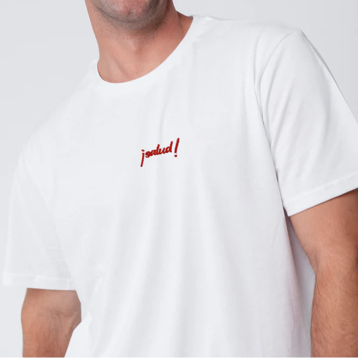 Eine Person, die ein schlichtes weißes T-Shirt trägt, auf dessen Brust in kleinen roten Buchstaben das Wort jolud! eingestickt ist. Das Gesicht der Person ist teilweise außerhalb des Rahmens.