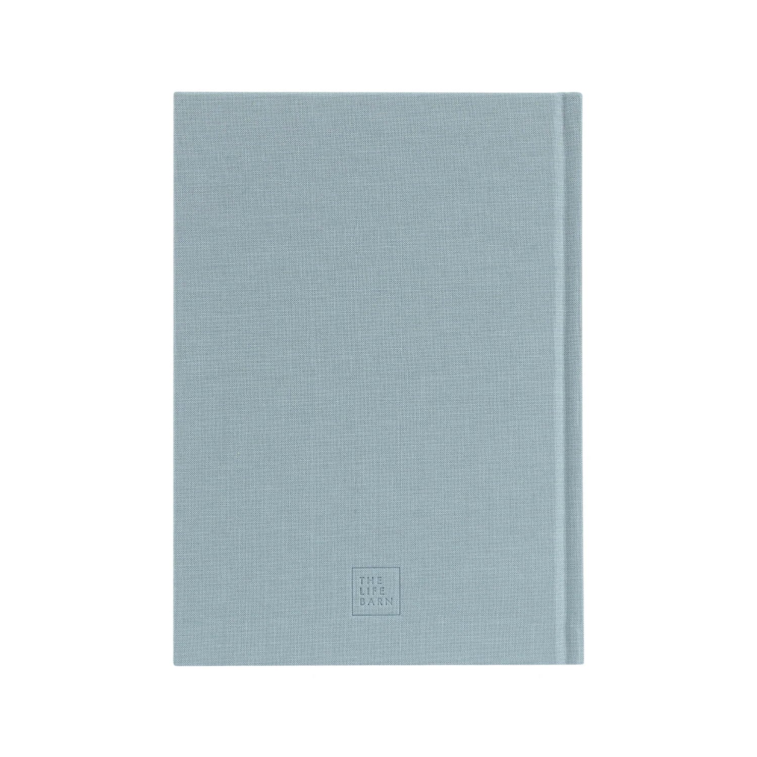 Ein geschlossenes, hellblaues Hardcover-Notizbuch mit einem dezent strukturierten Stoffeinband und der Aufschrift THE LIFE PLAN, die in kleinen Buchstaben in der Nähe der unteren Mitte geprägt ist. Der Hintergrund ist einfarbig weiß.