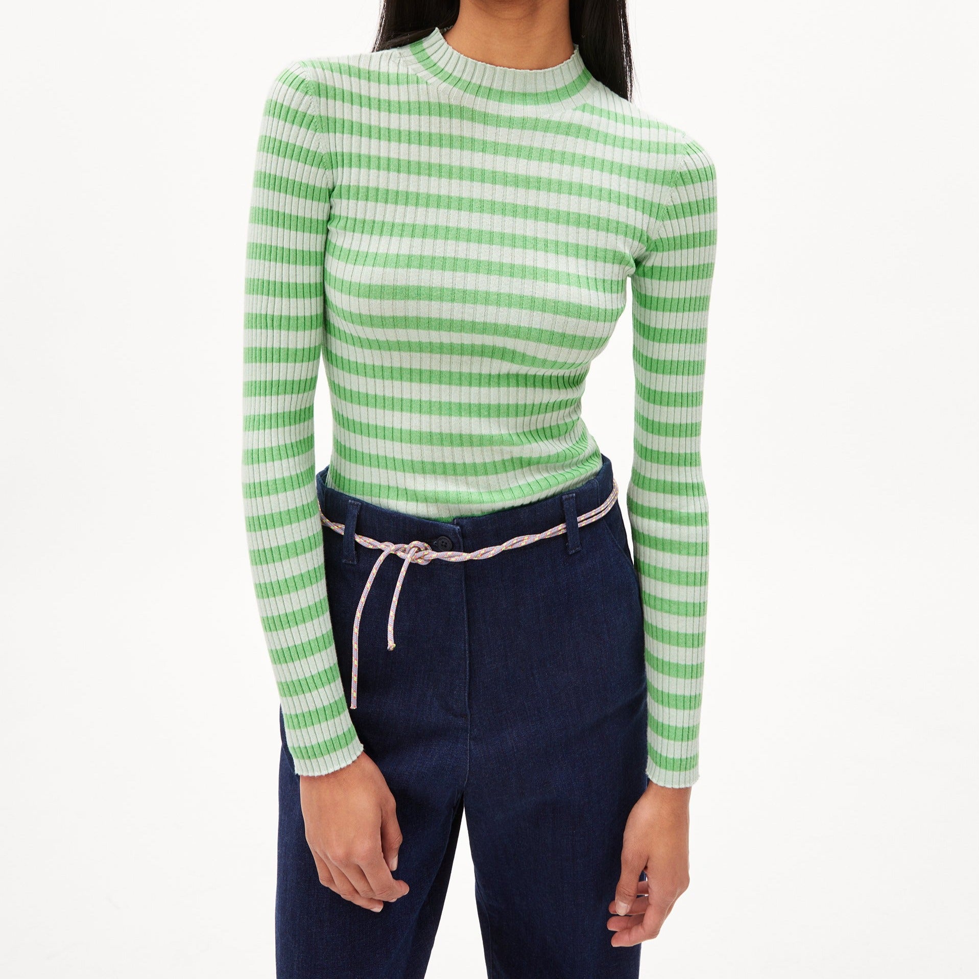 Person in a green and white striped long-sleeve top and blue jeans with a white rope belt, facing front.