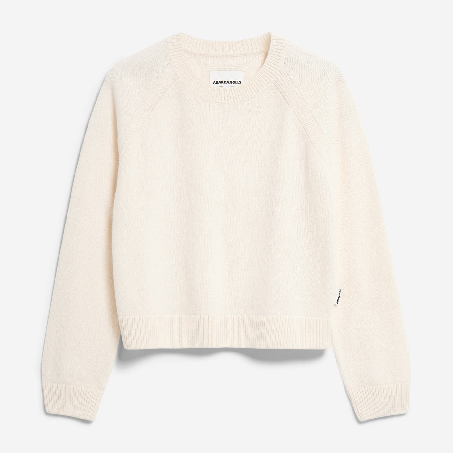 Ein cremefarbener, langärmeliger Strickpullover mit Rundhalsausschnitt und gerippten Bündchen, Saum und Kragen, flach auf weißem Grund.