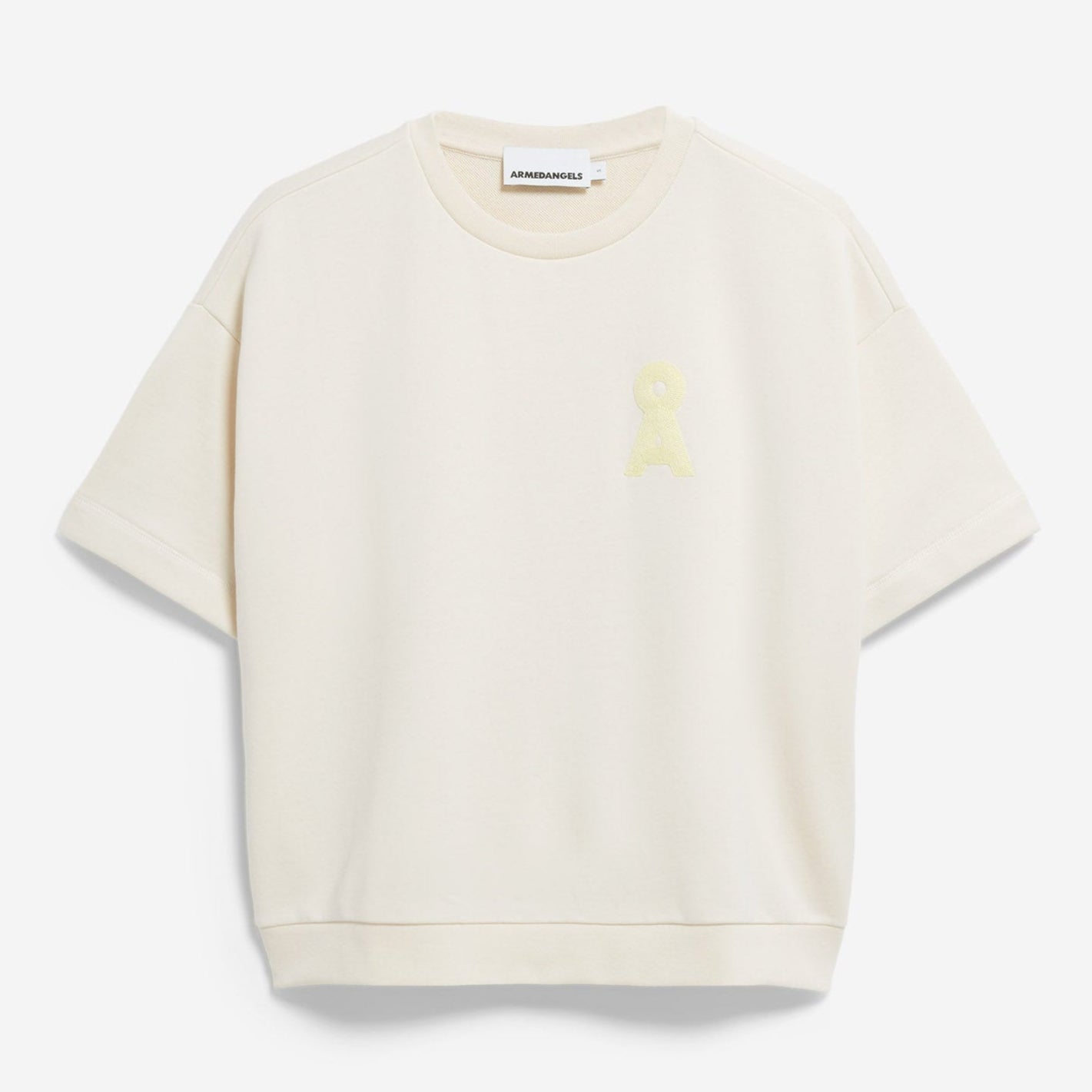 Ein kurzärmeliges, cremefarbenes Sweatshirt mit lockerer Passform und einem kleinen, hellgelben gestickten Aufnäher auf der linken Brust. Das Shirt ist auf einem schlichten weißen Hintergrund abgebildet.