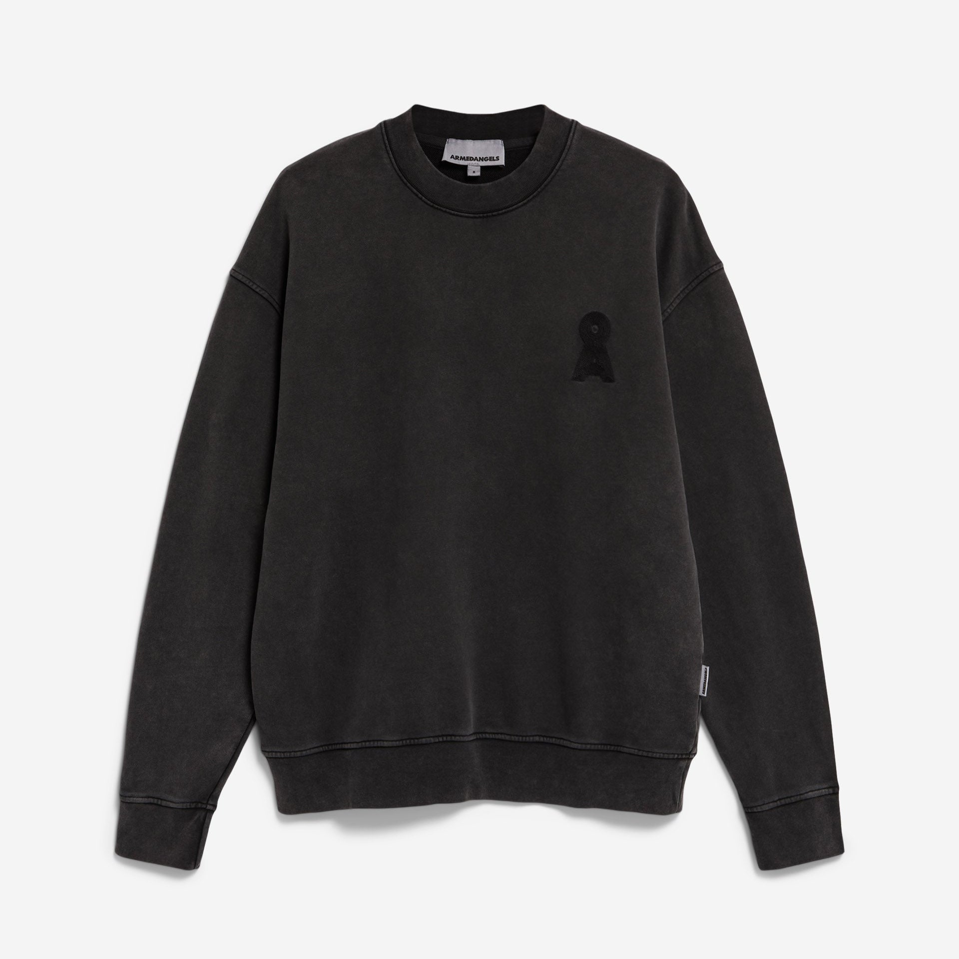 Ein schwarzes Sweatshirt mit Rundhalsausschnitt, langen Ärmeln, gerippten Bündchen und Saum sowie einem kleinen gestickten Aufnäher auf der linken Brust. Das Sweatshirt hat einen leicht verblassten Vintage-Look und eine lockere Passform.