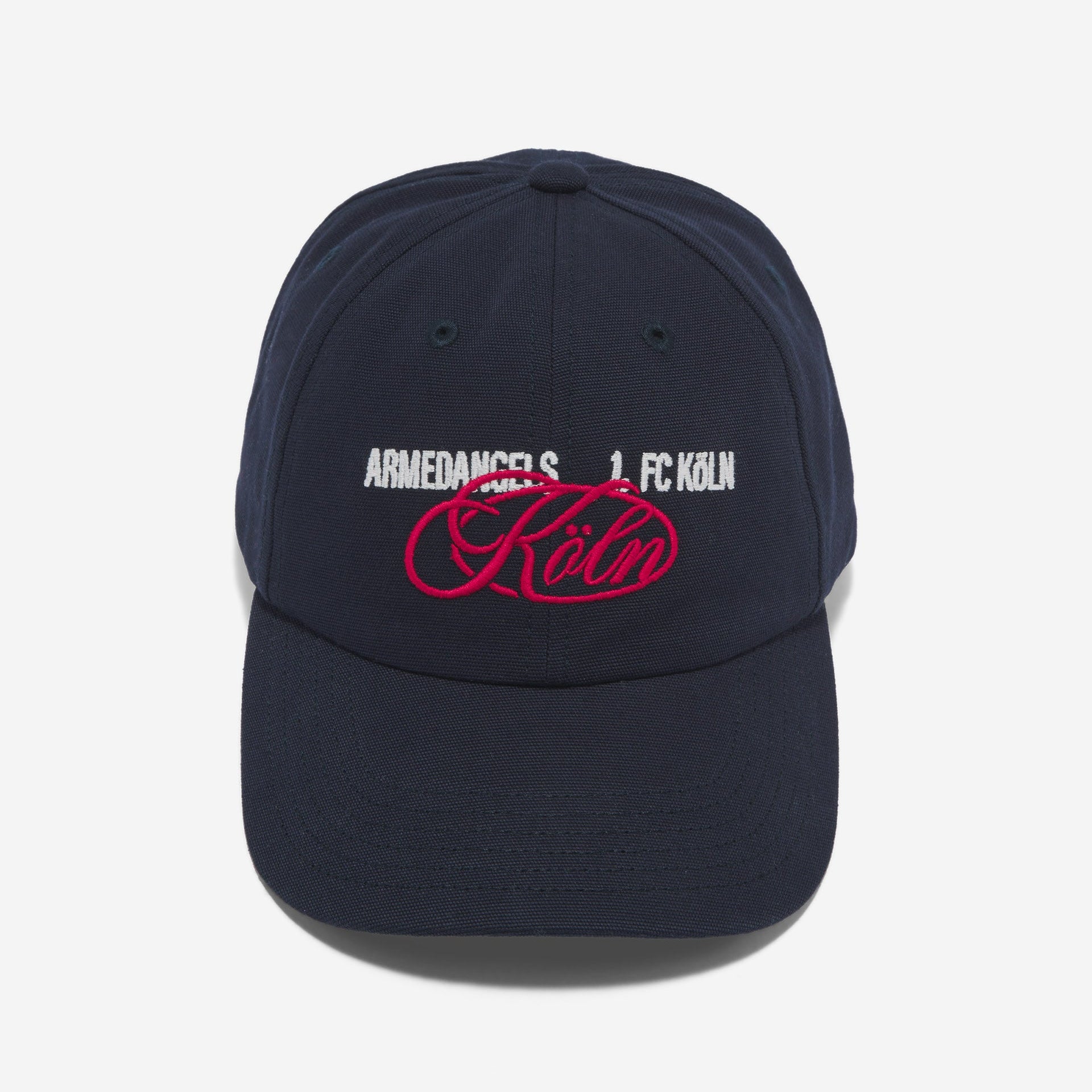 Eine marineblaue Baseballkappe mit weißem gesticktem Text ARMEDANGELS 1. FC KÖLN und einem großen rosa Schriftzug mit der Aufschrift Köln auf der Vorderseite. Die Kappe ist vor einem schlichten weißen Hintergrund abgebildet.