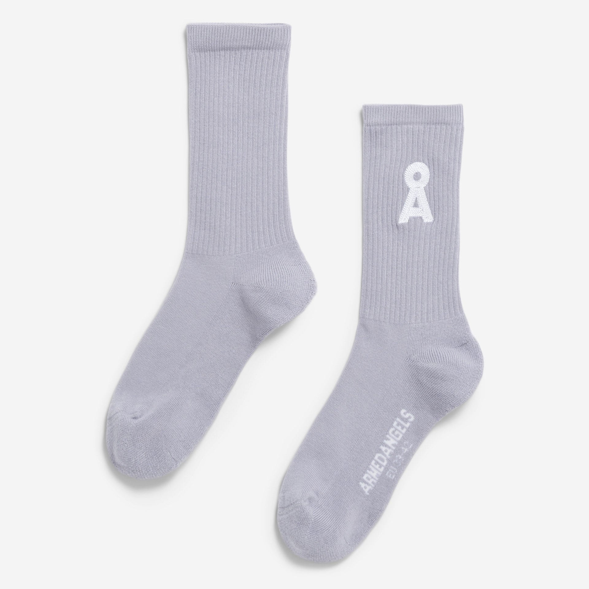Ein Paar hellgraue Ringelsocken. Eine Socke zeigt ein weißes gesticktes Symbol im oberen Bereich, die andere zeigt den Text ARIGATO ANGELS und OSLO im Zehenbereich. Die Socken sind flach auf einem weißen Hintergrund gelegt.
