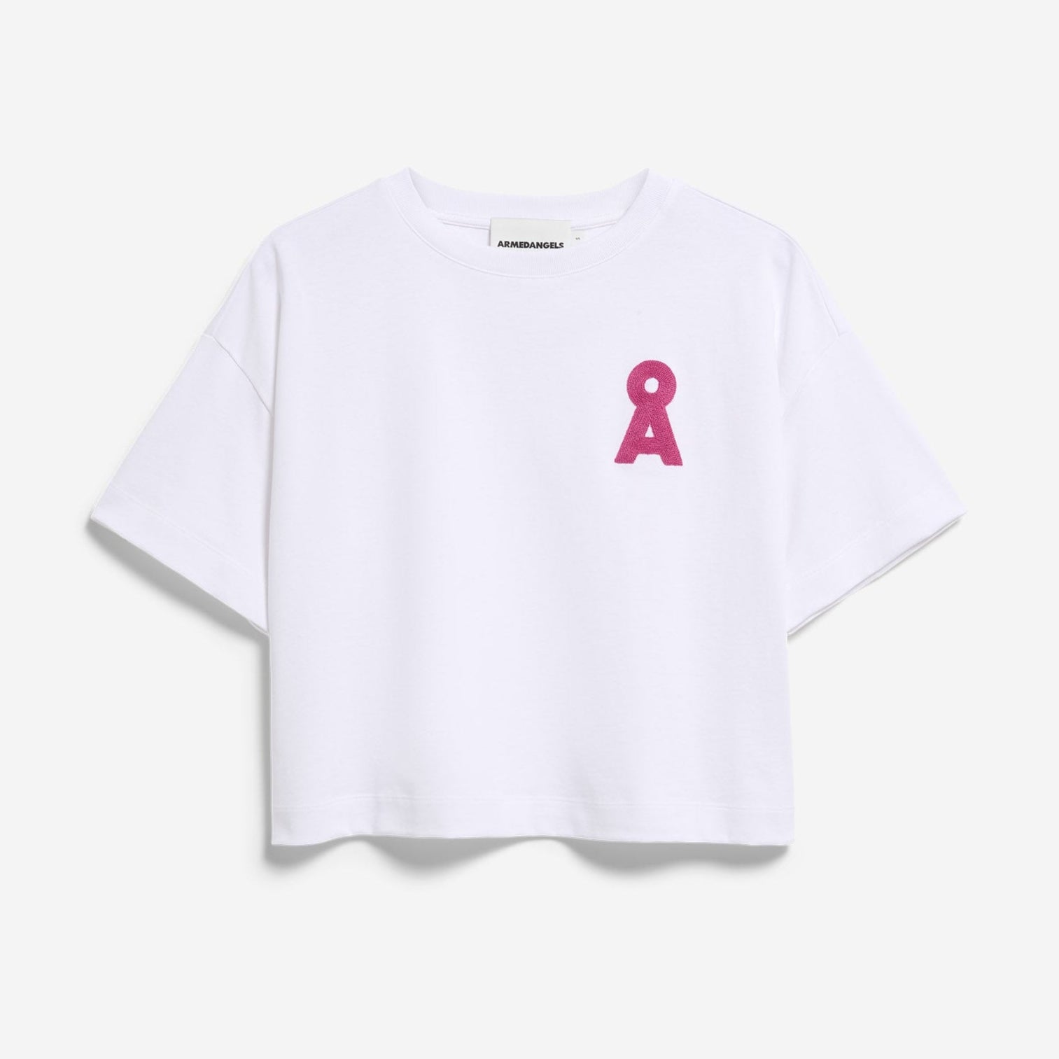 Ein schlichtes weißes, kurzärmeliges Crop-Top mit einem kleinen rosa Schleifensymbol auf der linken Brust vor weißem Hintergrund.