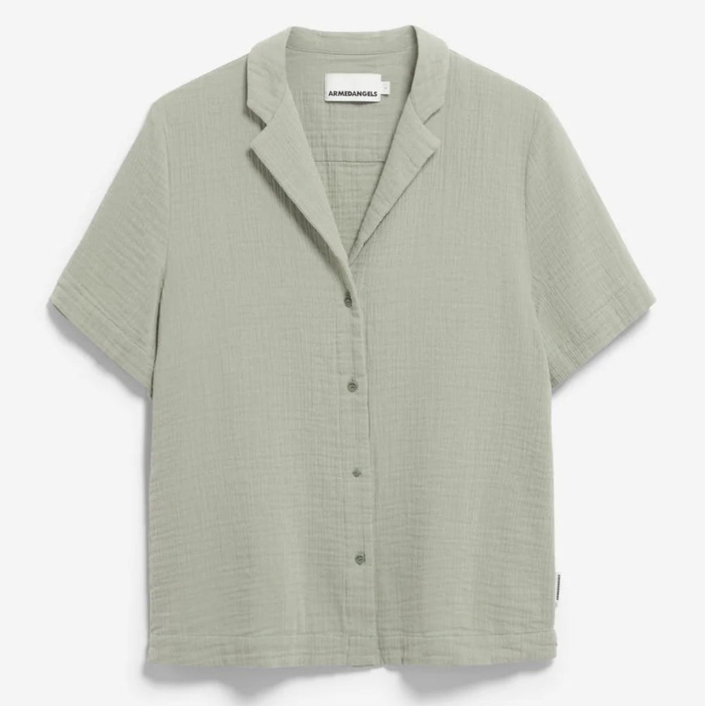Ein helles salbeigrünes, kurzärmeliges Button-up-Hemd aus strukturiertem Stoff mit einem lockeren Kragen auf einem einfarbig weißen Hintergrund.