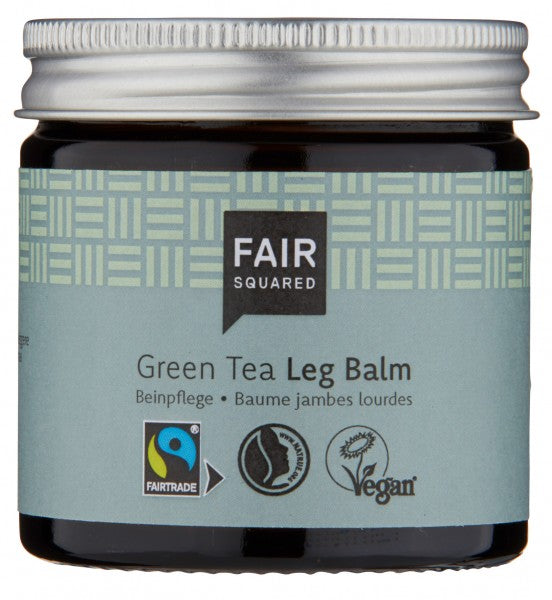Ein Tiegel Fair Squared Green Tea Leg Balm mit einem hellgrünen Etikett mit den Logos Fairtrade, Vegan und Umweltfreundlich. Der Tiegel hat einen silbernen Deckel und der Text ist auf Englisch, Deutsch und Französisch.