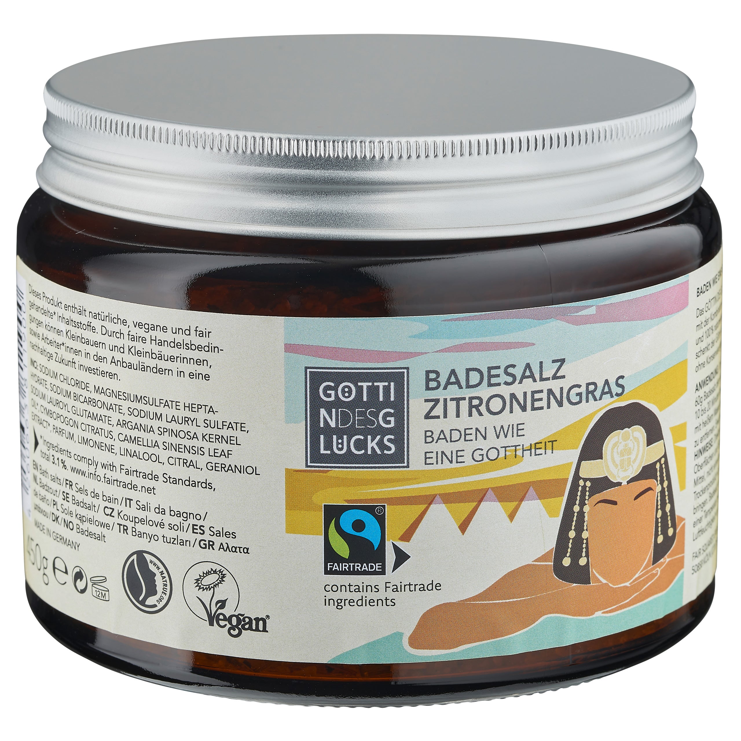 Eine braune Dose GötterGlücks Badesalz mit einem Etikett mit der Abbildung einer ägyptischen Königin, deutschem Text, Fairtrade- und Vegan-Logos sowie einer Zutatenliste auf der Seite.