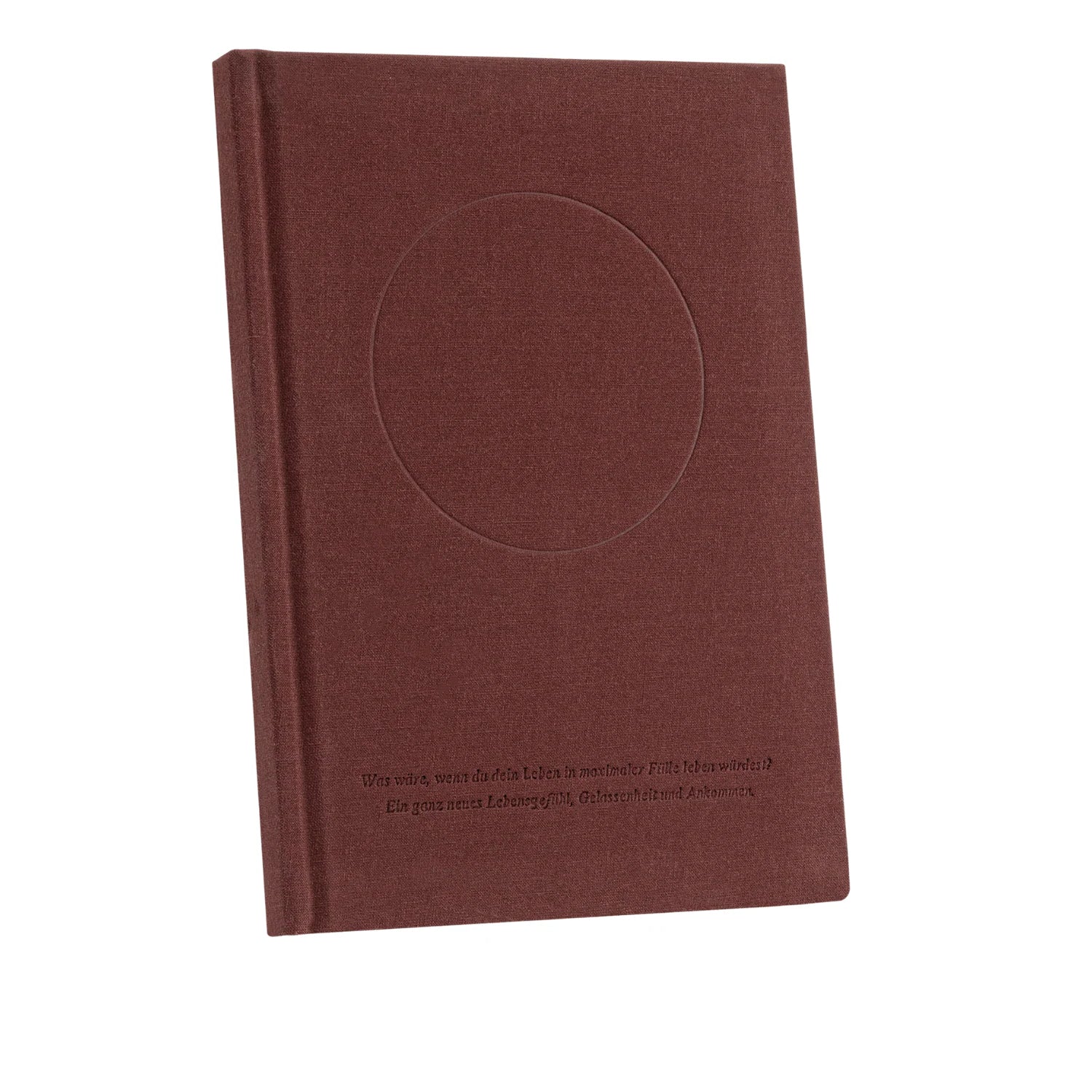 Ein gebundenes Buch mit strukturiertem, rotbraunem Einband, auf dem ein großer geprägter Kreis und eine geprägte Textzeile in deutscher Sprache am unteren Rand zu sehen sind. Das Buch steht aufrecht auf einem weißen Hintergrund.