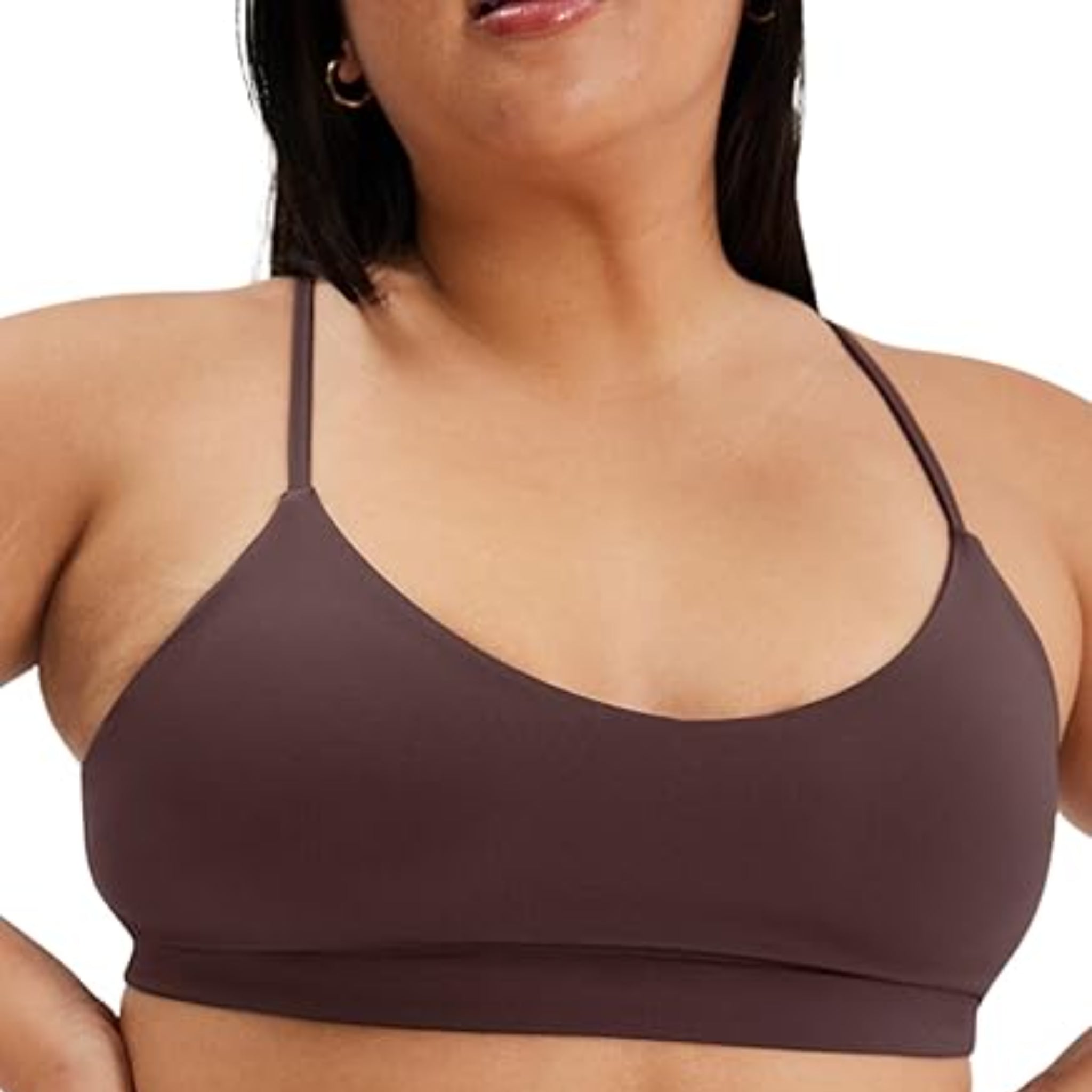 Eine Person, die einen braunen kabellosen Bralette mit dünnen Trägern trägt, der von den Schultern bis zur oberen Taille reicht, vor einem unifarbenen Hintergrund.