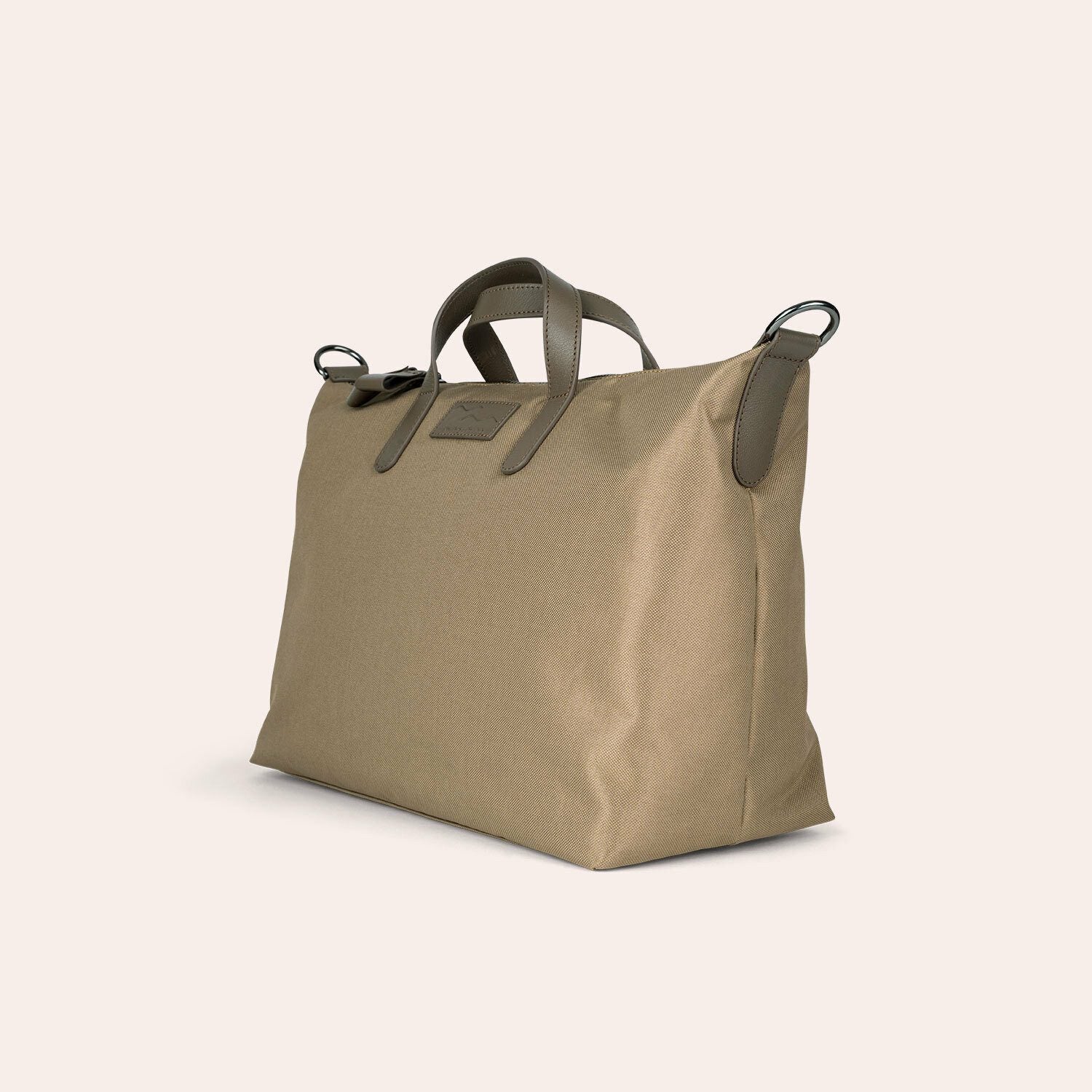 Eine hellbraune Tragetasche mit kurzen Griffen und dunklen Akzentschlaufen an den oberen Ecken, die vor einem schlichten hellen Hintergrund präsentiert wird.