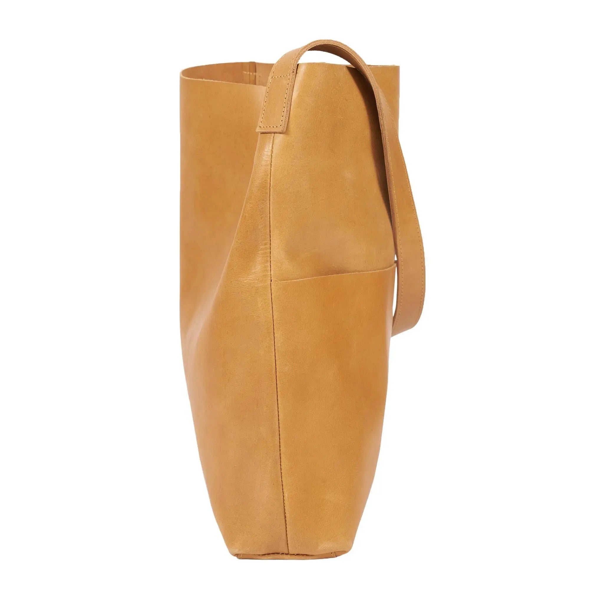 Tan Leder Tote Bag in einer Seitenansicht, mit einem einzigen Riemen und einem minimalistischen, schlichten Design mit sichtbaren Nähten.