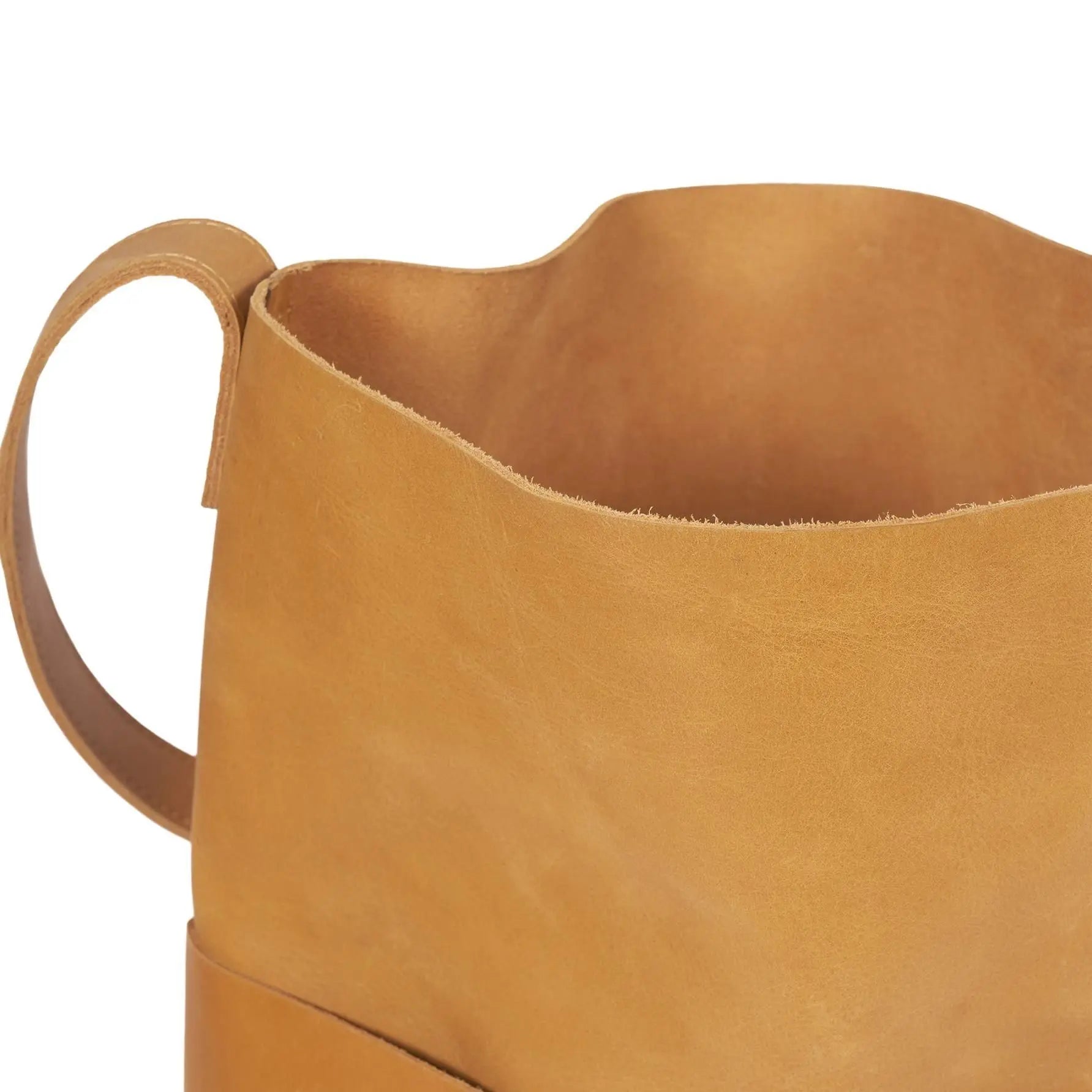 Nahaufnahme der Oberseite und der Seite eines hellbraunen Lederstiefels, die die Zuglasche, die glatte Textur und die Nähte zeigt.