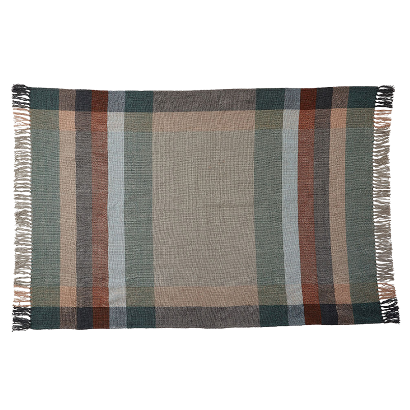 Eine rechteckige gewebte Decke mit einem Karomuster in gedeckten Grün-, Braun-, Beige- und Blautönen und mit Fransen an den kürzeren Seiten.