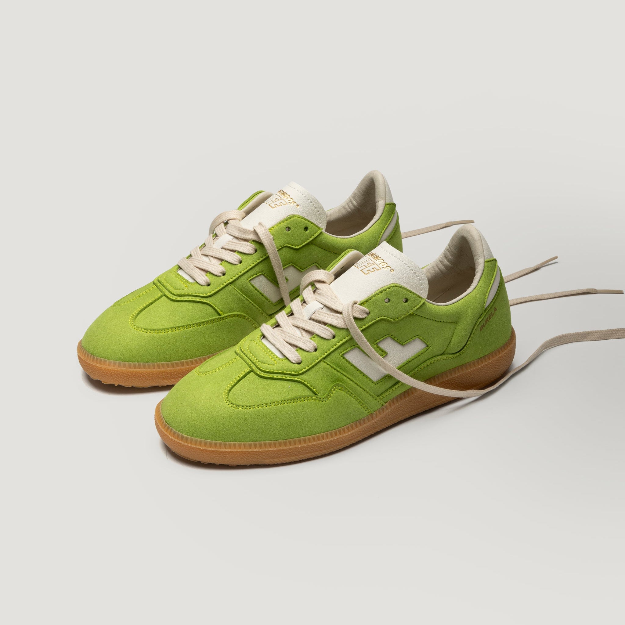 Ein Paar hellgrüne Turnschuhe mit beigen Schnürsenkeln und Sohlen, mit weißen Akzenten und einem weißen Logo an der Seite, das auf einem schlichten weißen Hintergrund dargestellt ist.