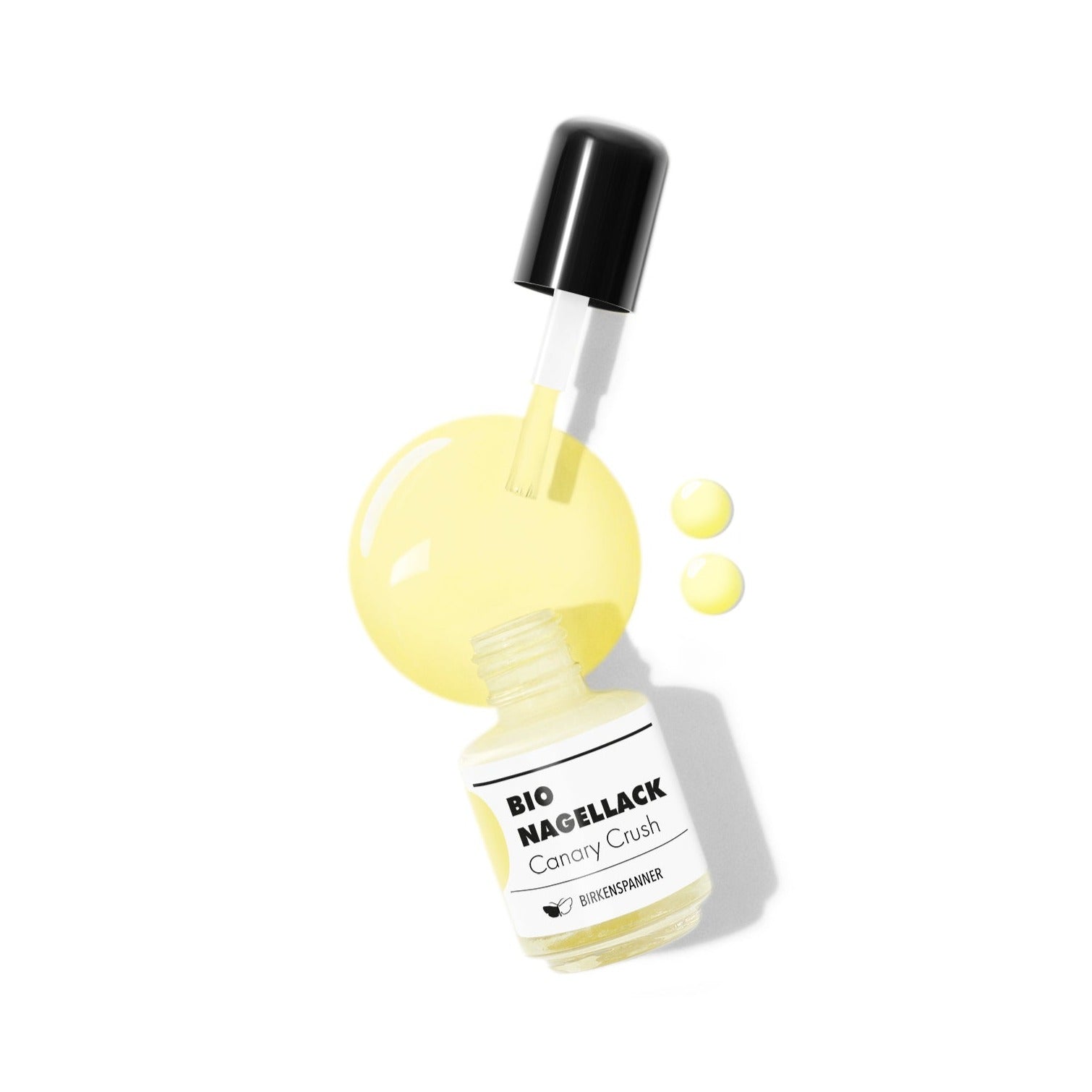 Gelber Nagellack in offenem Fläschchen mit Pinsel und Klecksen auf weißem Hintergrund.