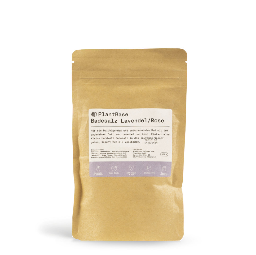 Ein brauner, wiederverschließbarer Beutel mit der Aufschrift PlantBase Badesalz Lavendel/Rose und Produktinformationen in deutscher Sprache, der Badesalz enthält. Auf dem Etikett sind Symbole und Text auf einem schlichten weißen Hintergrund abgebildet.