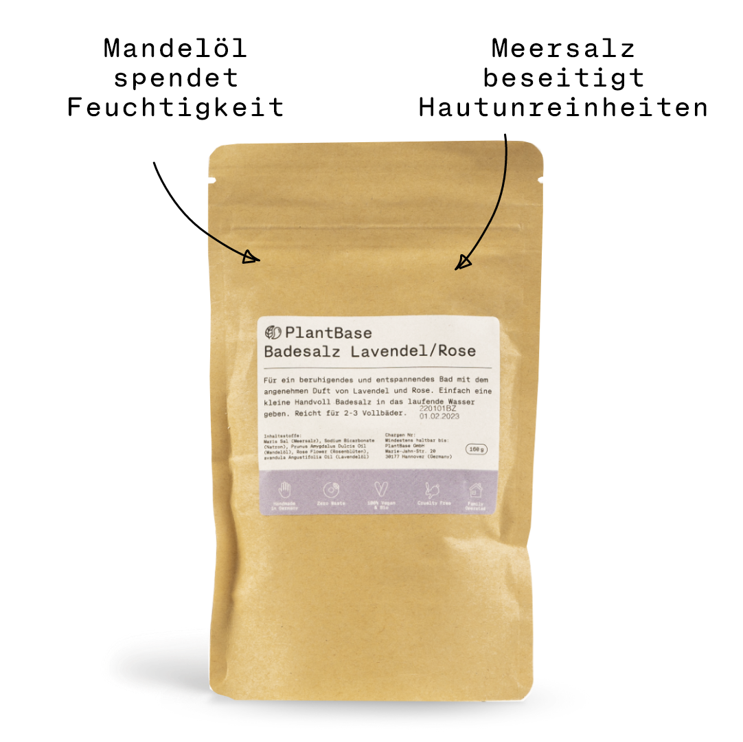 Ein brauner wiederverschließbarer Beutel mit der Aufschrift PlantBase Badesalz Lavendel/Rose mit weißem Etikett und schwarzem Text, aufrecht stehend auf weißem Hintergrund. Die Verpackung ist am unteren Rand mit kleinen Symbolen und Informationen versehen.
