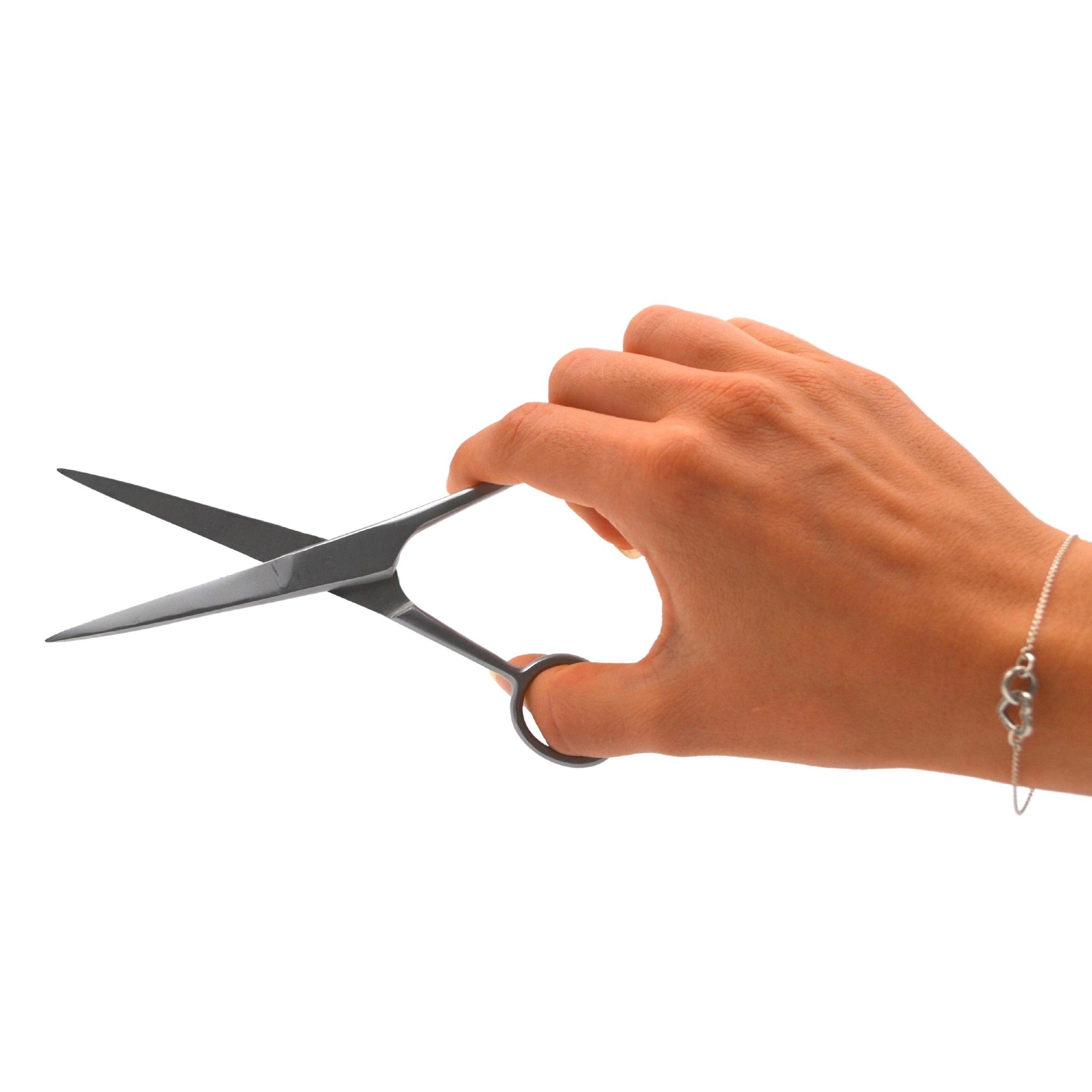 Eine rechte Hand hält eine offene Schere, bereit zum Schneiden. Die Hand trägt ein zartes Silberarmband, und der Hintergrund ist schlicht weiß.