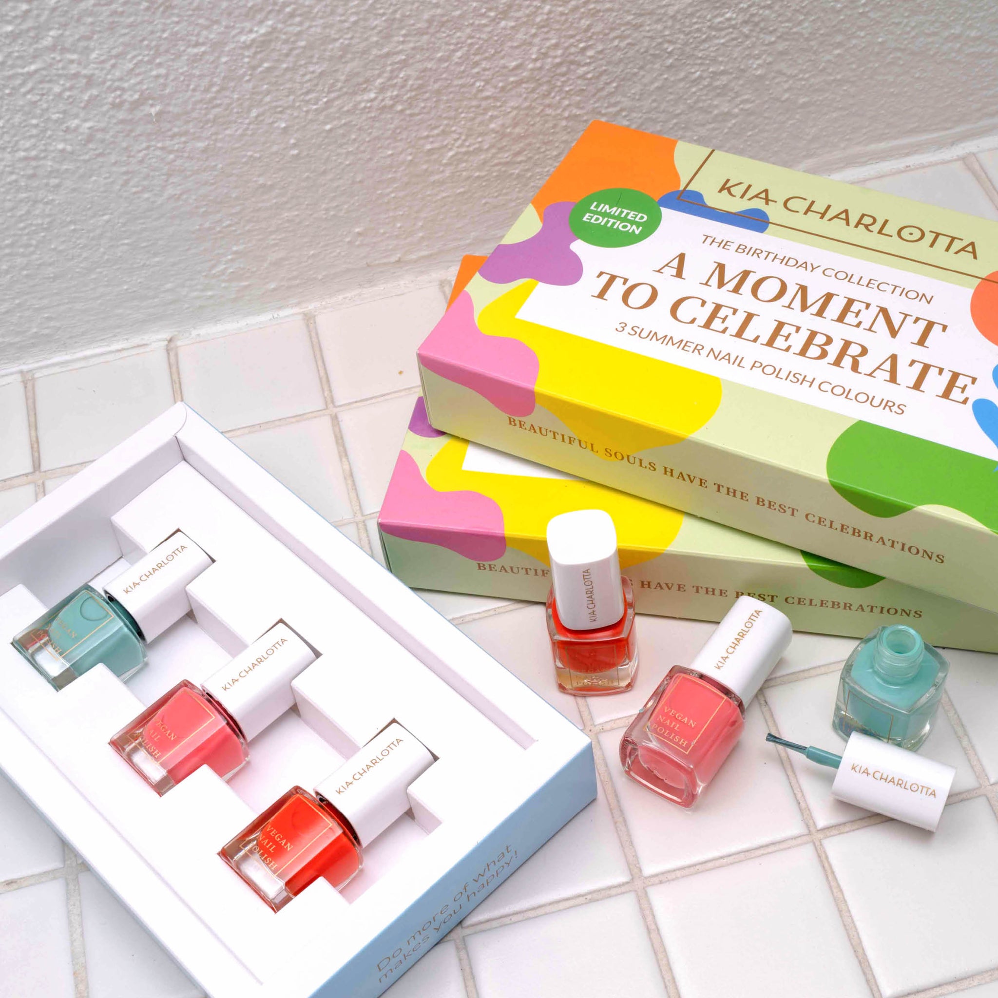 Bunte Nagellacke und Geschenkboxen von Kia-Charlotta auf einem weißen Fliesenboden.