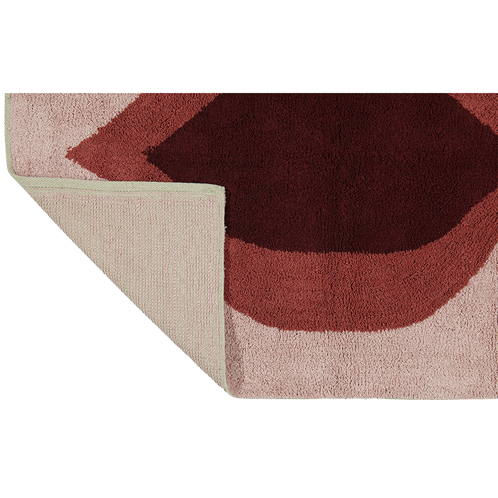 Ein rechteckiger Teppich mit abstrakten Formen in Rosa- und Burgundtönen; eine Ecke ist umgeschlagen, so dass die einfarbige hellrosa Unterseite sichtbar wird.