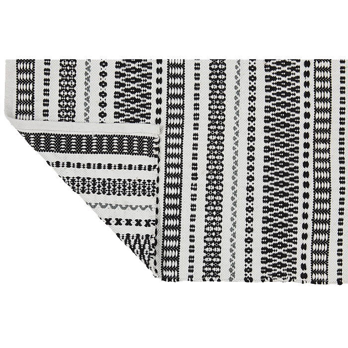 Ein schwarz-weißer Webteppich mit verschiedenen geometrischen Mustern und Streifen. Eine Ecke ist umgeschlagen, um die Rückseite des Teppichs zu zeigen.