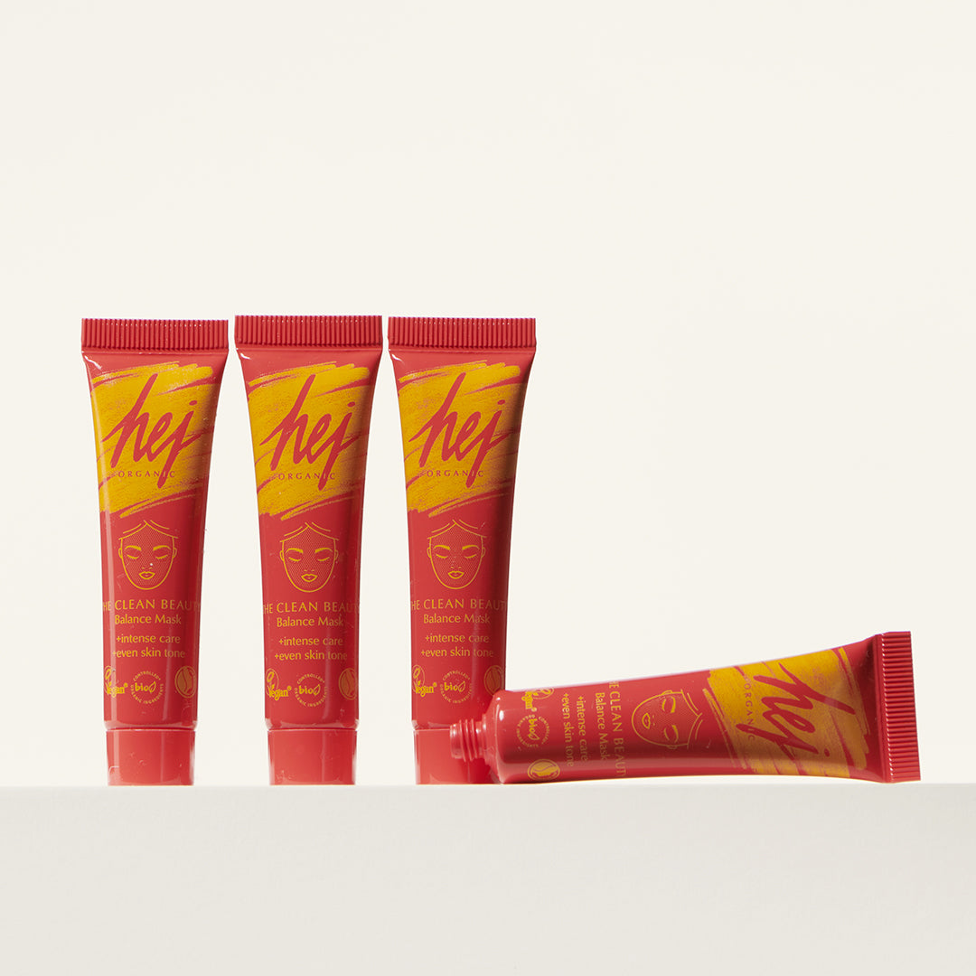 Vier rote Tuben mit gelbem Aufdruck und Gesichtsmaske-Design; drei stehen aufrecht, eine liegt horizontal.