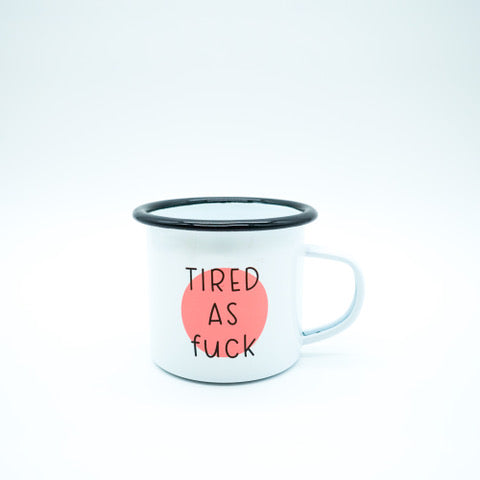 Weißer Emaillebecher mit schwarzem Rand und rotem Punkt, darauf der Text "TIRED AS FUCK".