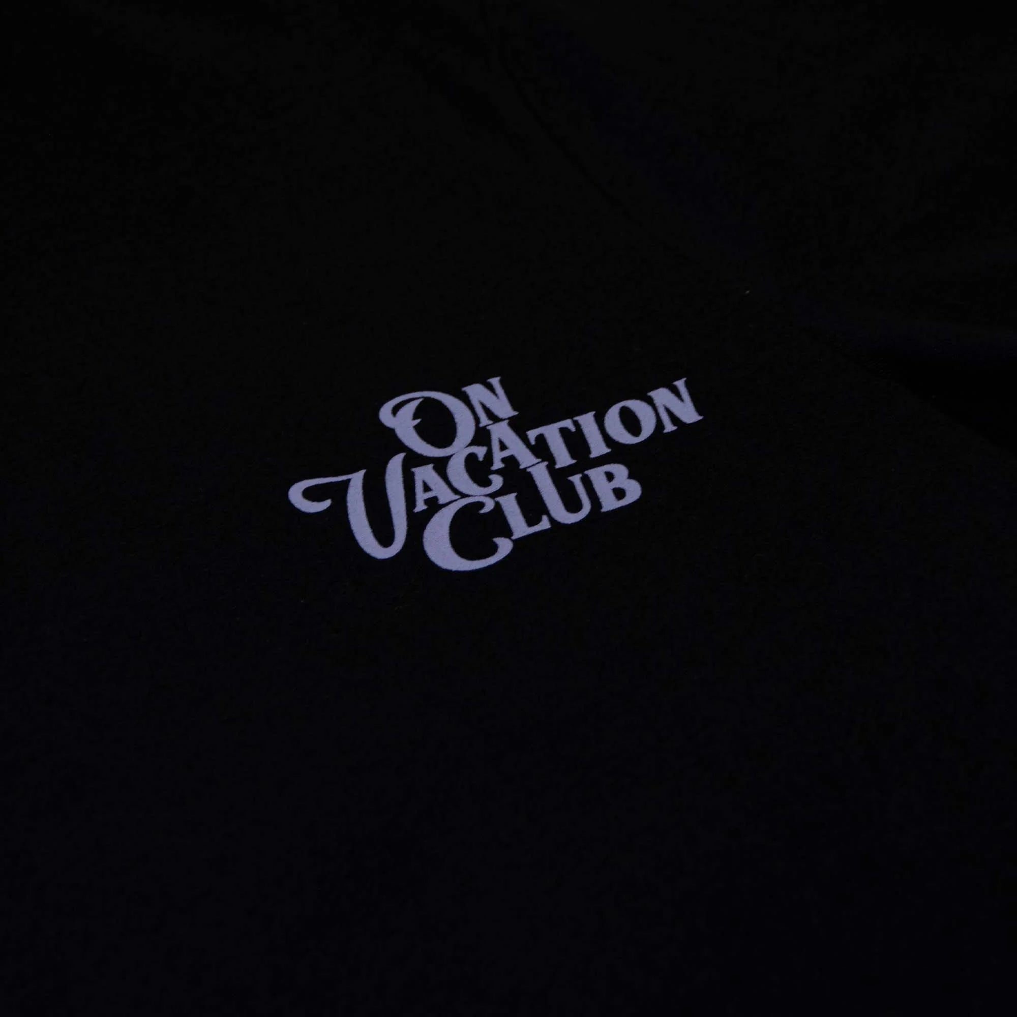 Schwarzes T-Shirt mit der Aufschrift "On Vacation Club" in weißem, vintage Stil.