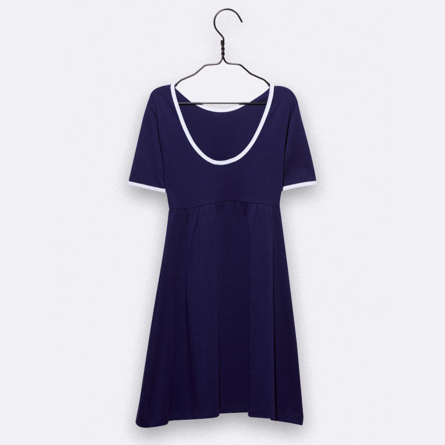 Ein kurzärmeliges, knielanges, marineblaues Kleid mit weißem Rundhalsausschnitt und weißem Ärmelbesatz, das auf einem schwarzen Bügel vor einem schlichten hellen Hintergrund hängt.