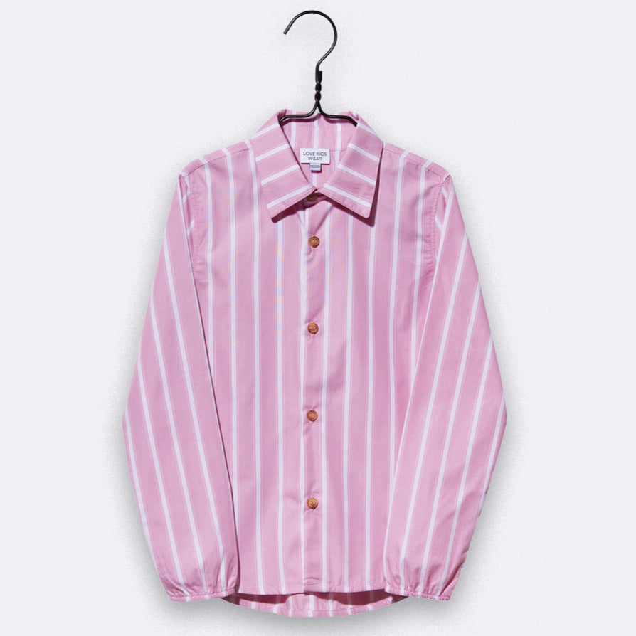 Ein langärmeliges, rosafarbenes Button-up-Hemd mit weißen vertikalen Streifen ist auf einem schwarzen Bügel vor einem schlichten, hellen Hintergrund ausgestellt.