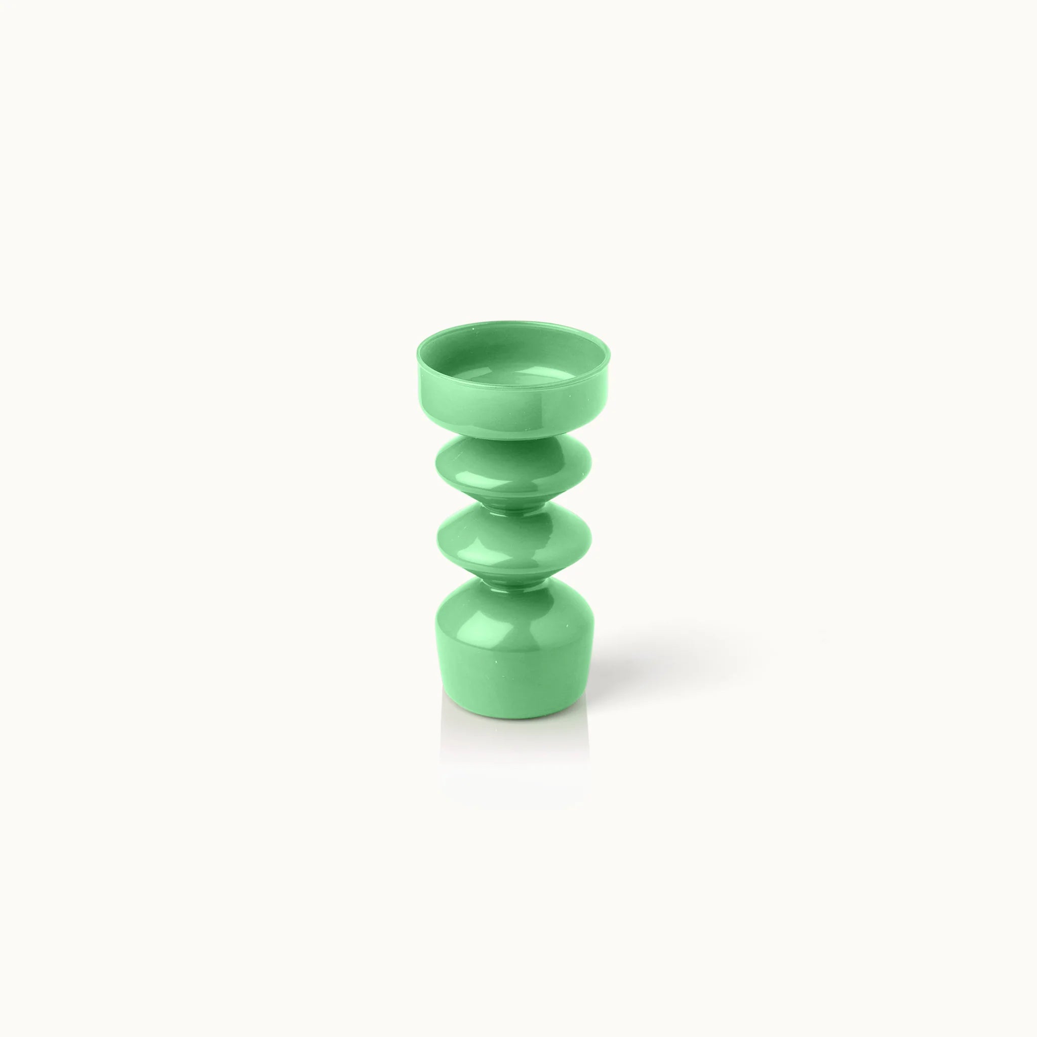 Eine moderne, glänzend grüne Vase mit einem symmetrischen, skulpturalen Design mit runden und gestapelten geometrischen Formen vor einem schlichten weißen Hintergrund.