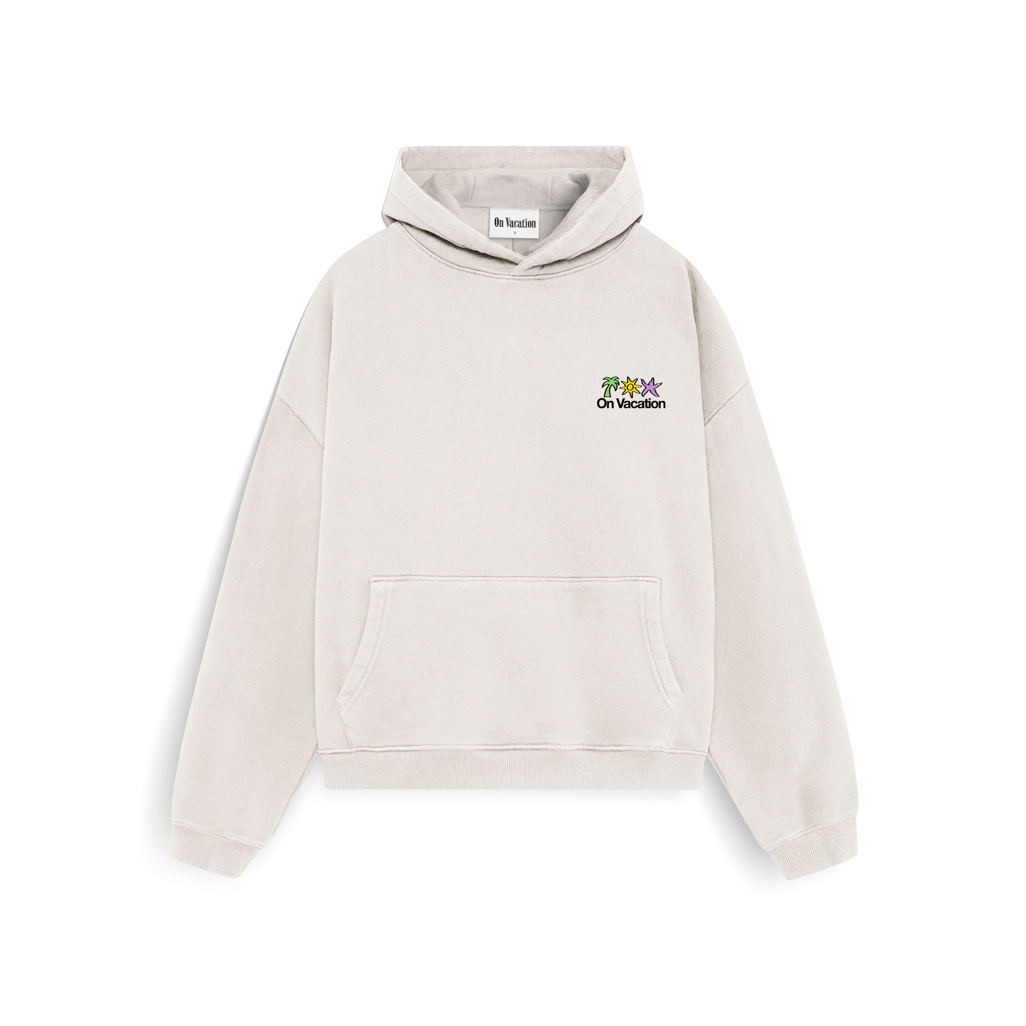 Ein hellbeiger Kapuzenpullover mit einer Vordertasche, einer Kapuze und einem kleinen gestickten Motiv und dem Schriftzug On Vacation auf der linken Brustseite.