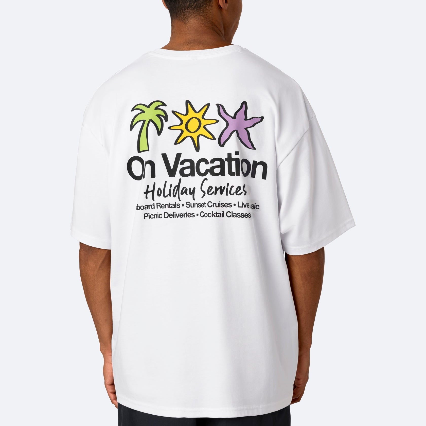 Eine Person trägt ein weißes T-Shirt mit bunten Bildern einer Palme, der Sonne und eines Seesterns sowie dem Text On Vacation Holiday Services und einer Liste von Urlaubsaktivitäten auf der Rückseite.