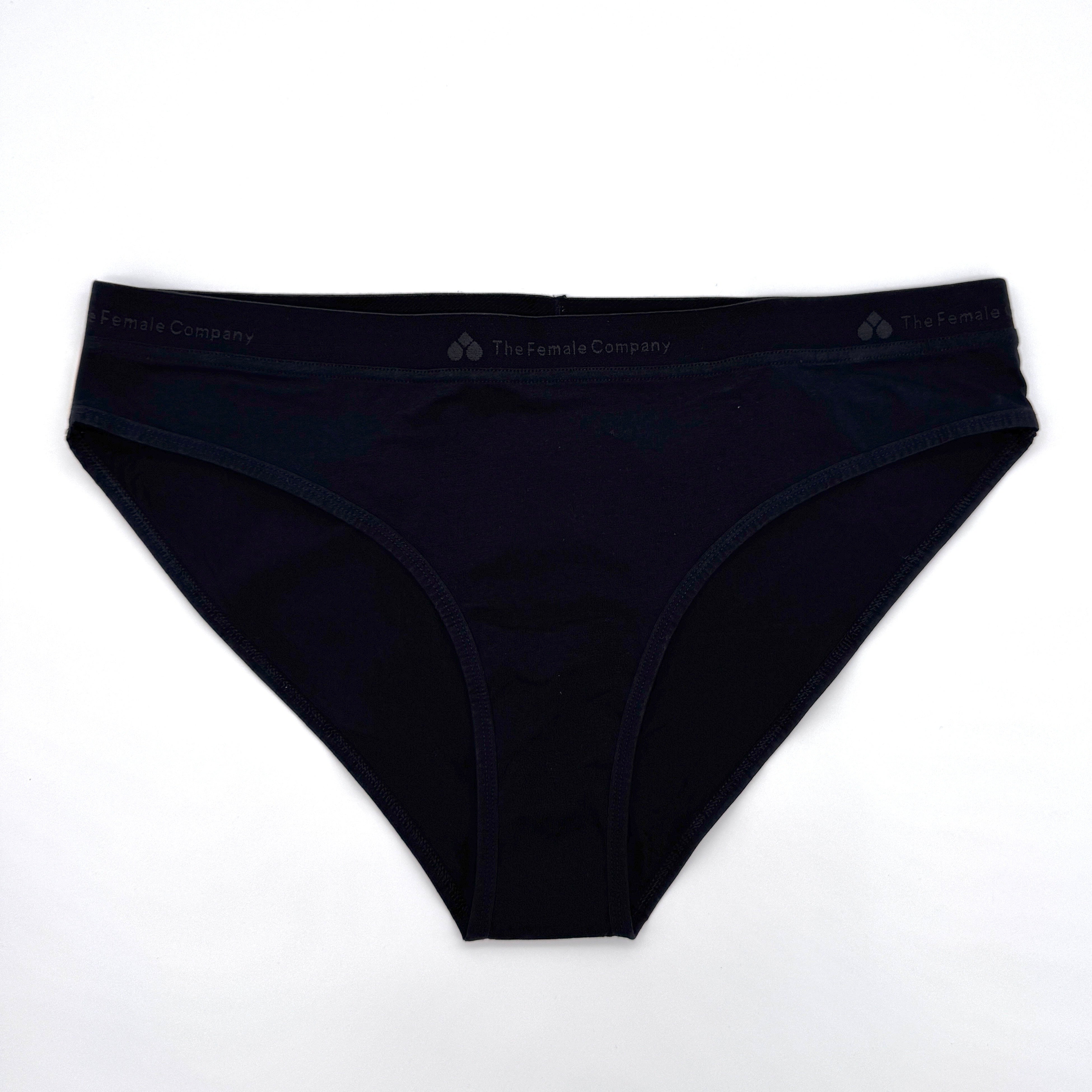 Ein Paar schwarze Damenunterwäsche mit nahtlosem Design, flach auf weißem Hintergrund. Auf dem Bund befindet sich ein dezentes Branding mit der Aufschrift The Female Company.