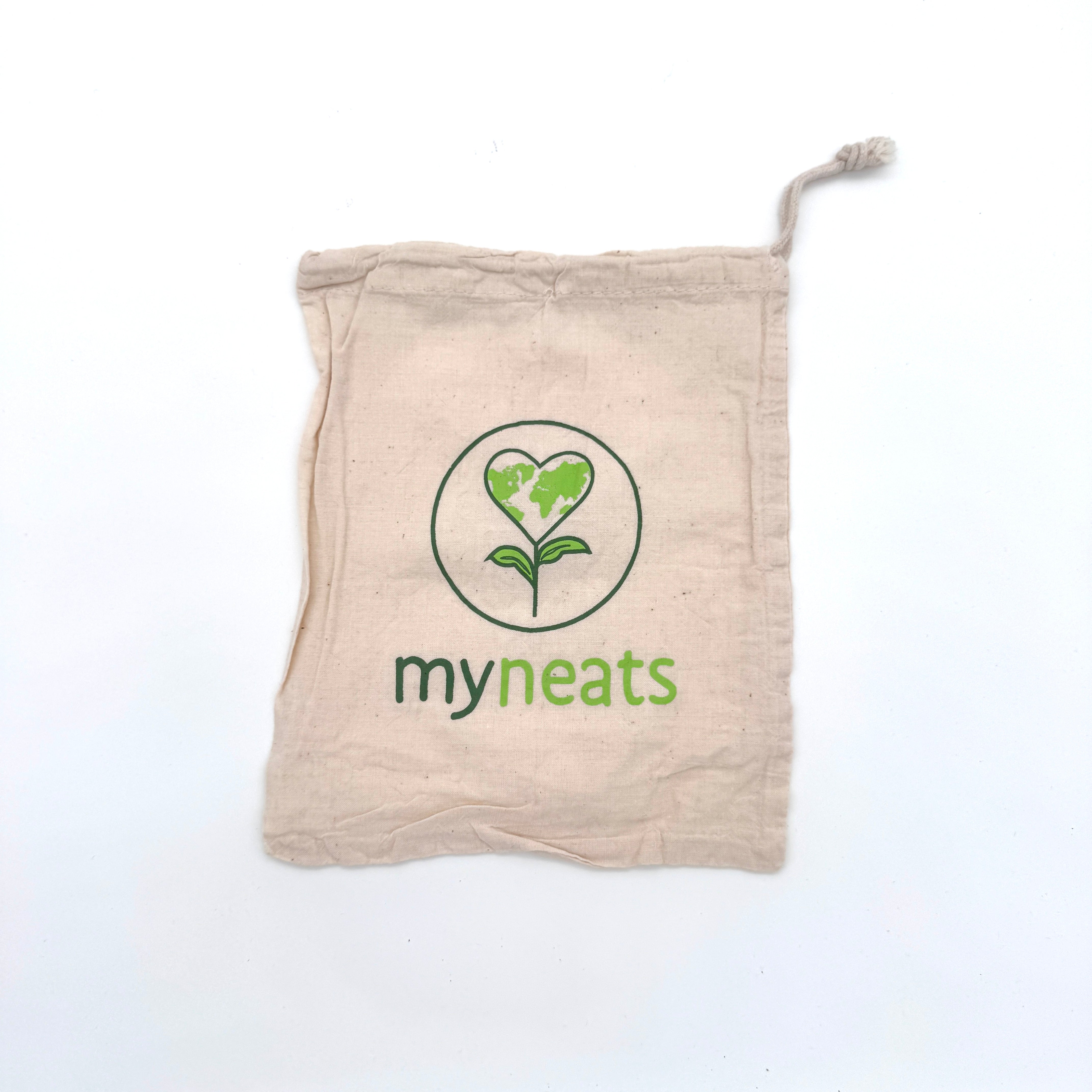 Eine beigefarbene Baumwolltasche mit Kordelzug, auf der das grüne Logo einer herzförmigen Erde über einem Pflanzenstamm und darunter das Wort myneats aufgedruckt ist. Die Tasche liegt flach auf einem weißen Hintergrund.
